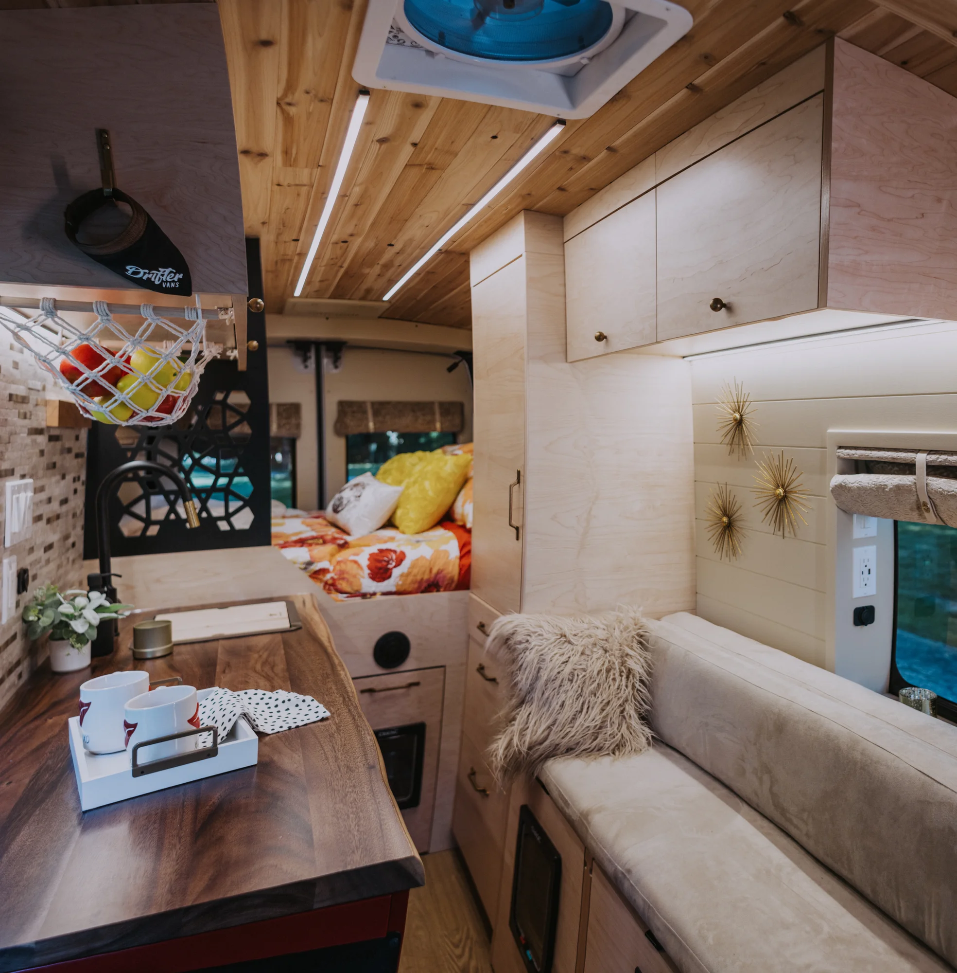 The Drifter 101 custom Ford Transit campervan built for Kim by Drifter Vans, Drifter layout with floral bedding, wood ceiling, and black shower fixtures