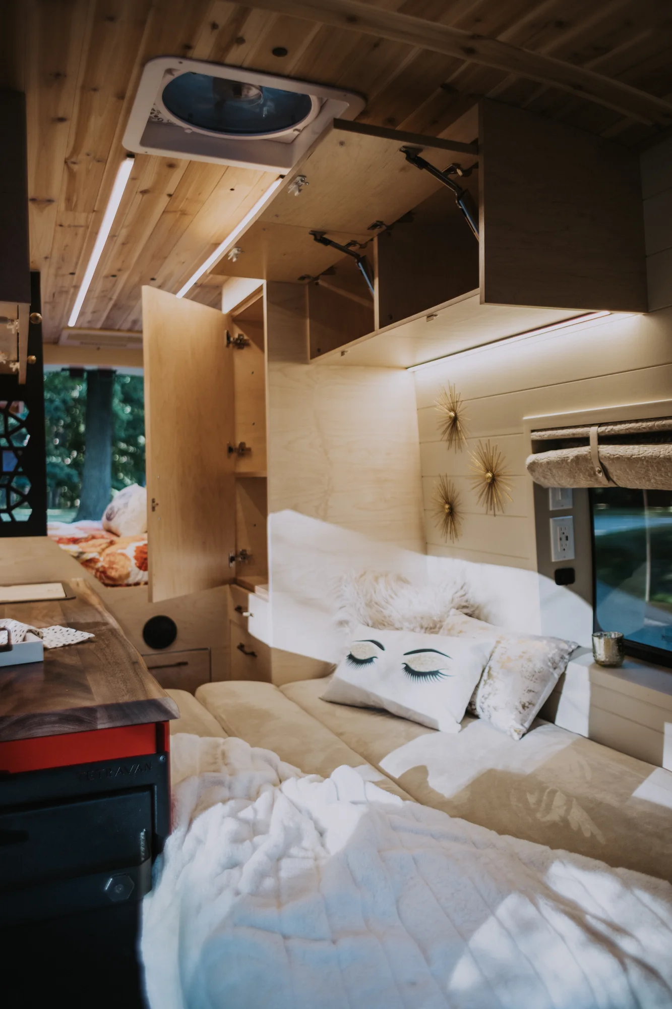 The Drifter 101 custom Ford Transit campervan built for Kim by Drifter Vans, Drifter layout with floral bedding, wood ceiling, and black shower fixtures