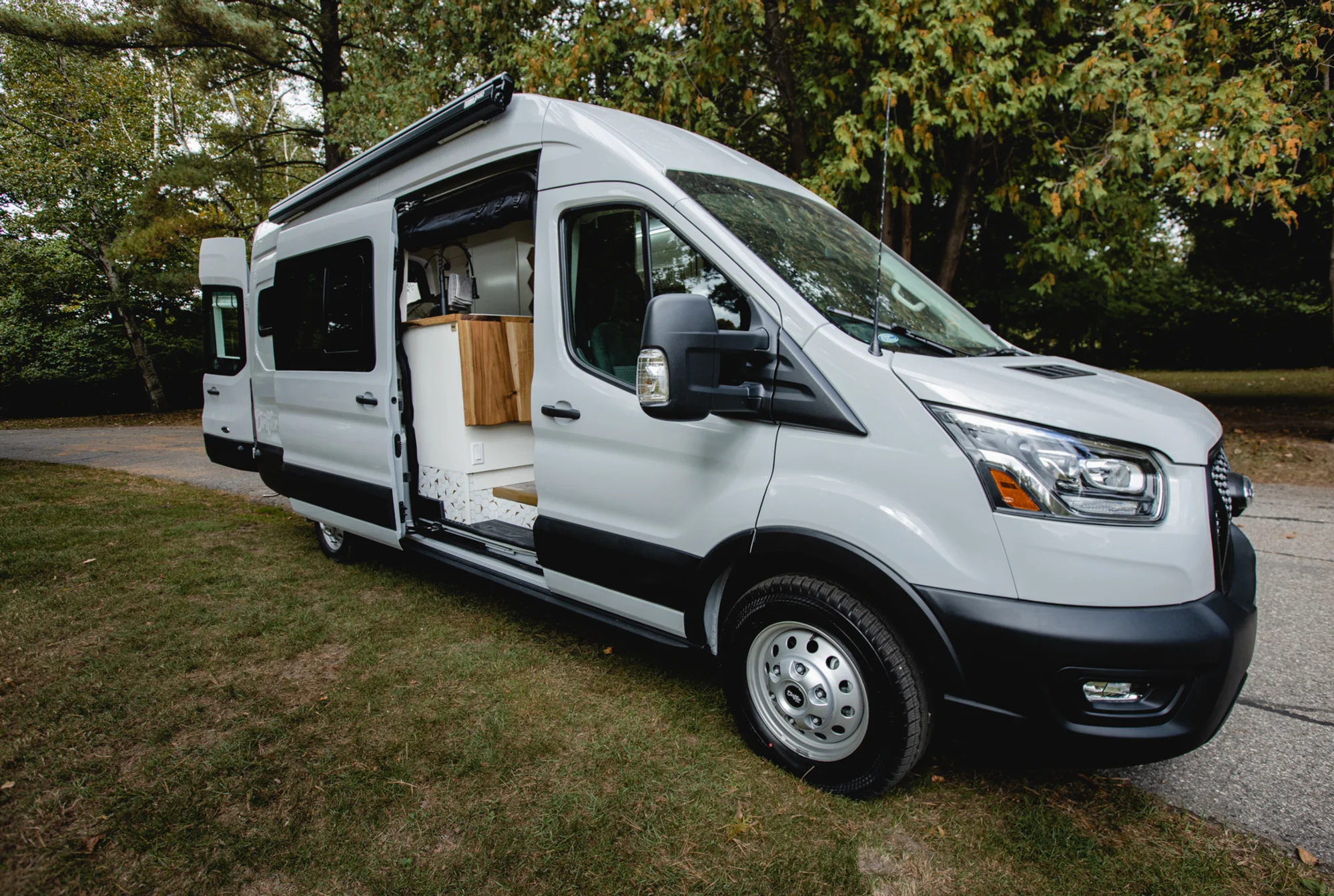 The Drifter 101 custom Ford Transit campervan built for Tess by Drifter Vans, Wanderer layout with a Nordic interior, white shiplap walls, wood ceiling, and gray seating