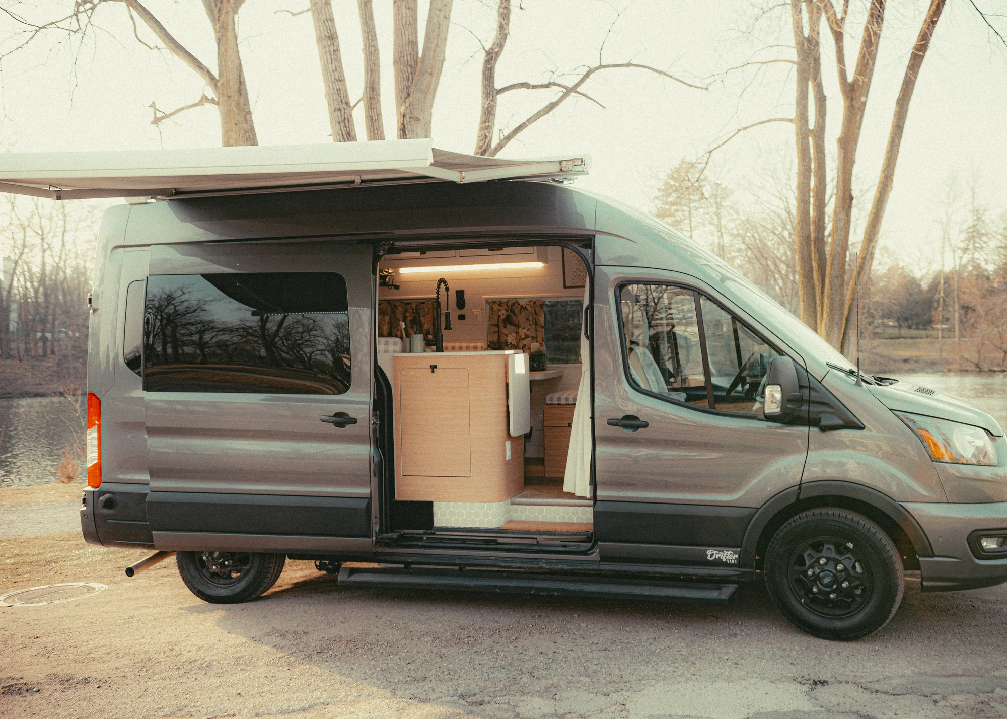 The Drifter 101 custom Ford Transit campervan built for Donna and Stanley by Drifter Vans, farmhouse interior with butcher block countertop, checkered cushions, and floral curtains