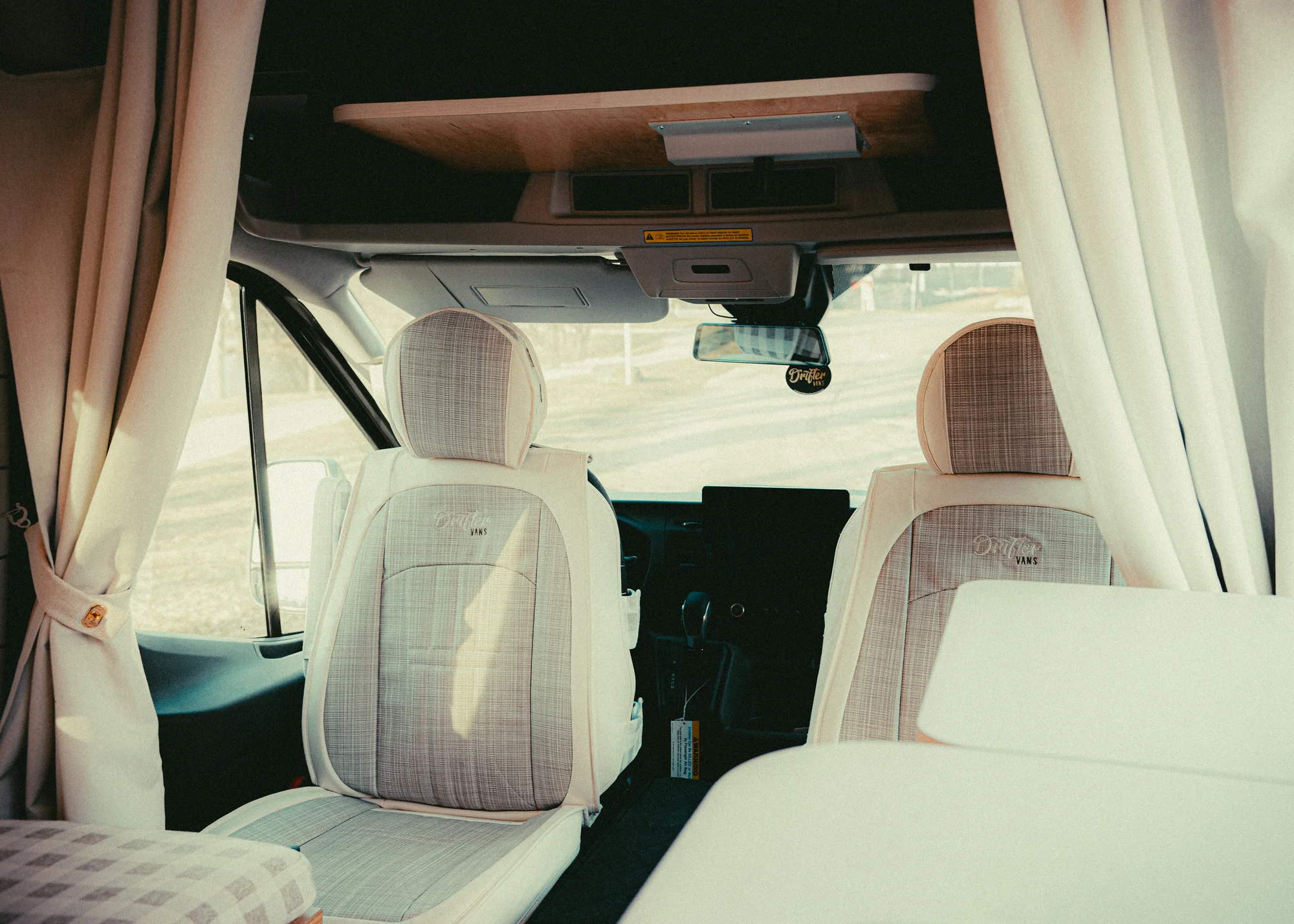 The Drifter 101 custom Ford Transit campervan built for Donna and Stanley by Drifter Vans, farmhouse interior with butcher block countertop, checkered cushions, and floral curtains