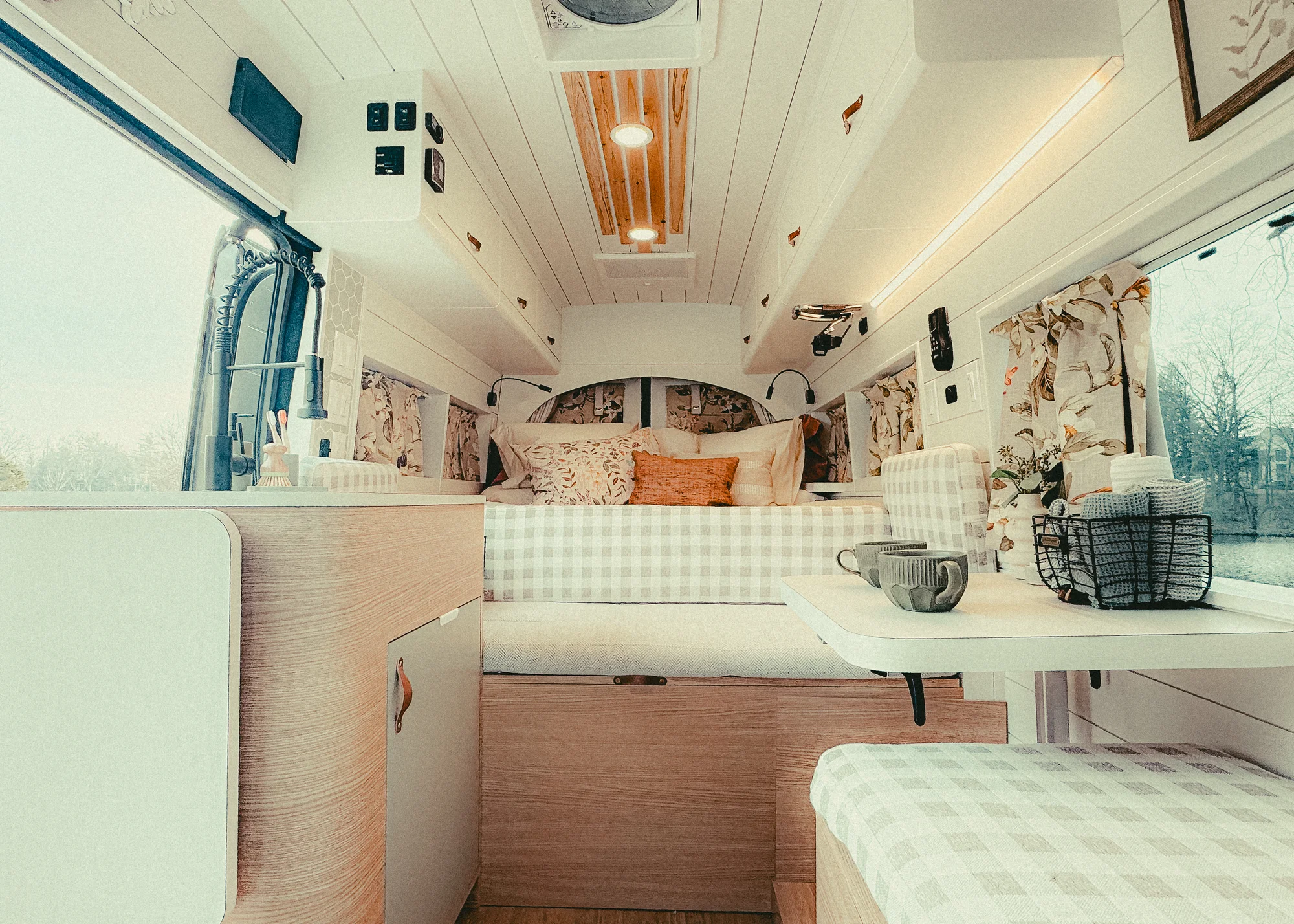 The Drifter 101 custom Ford Transit campervan built for Donna and Stanley by Drifter Vans, farmhouse interior with butcher block countertop, checkered cushions, and floral curtains