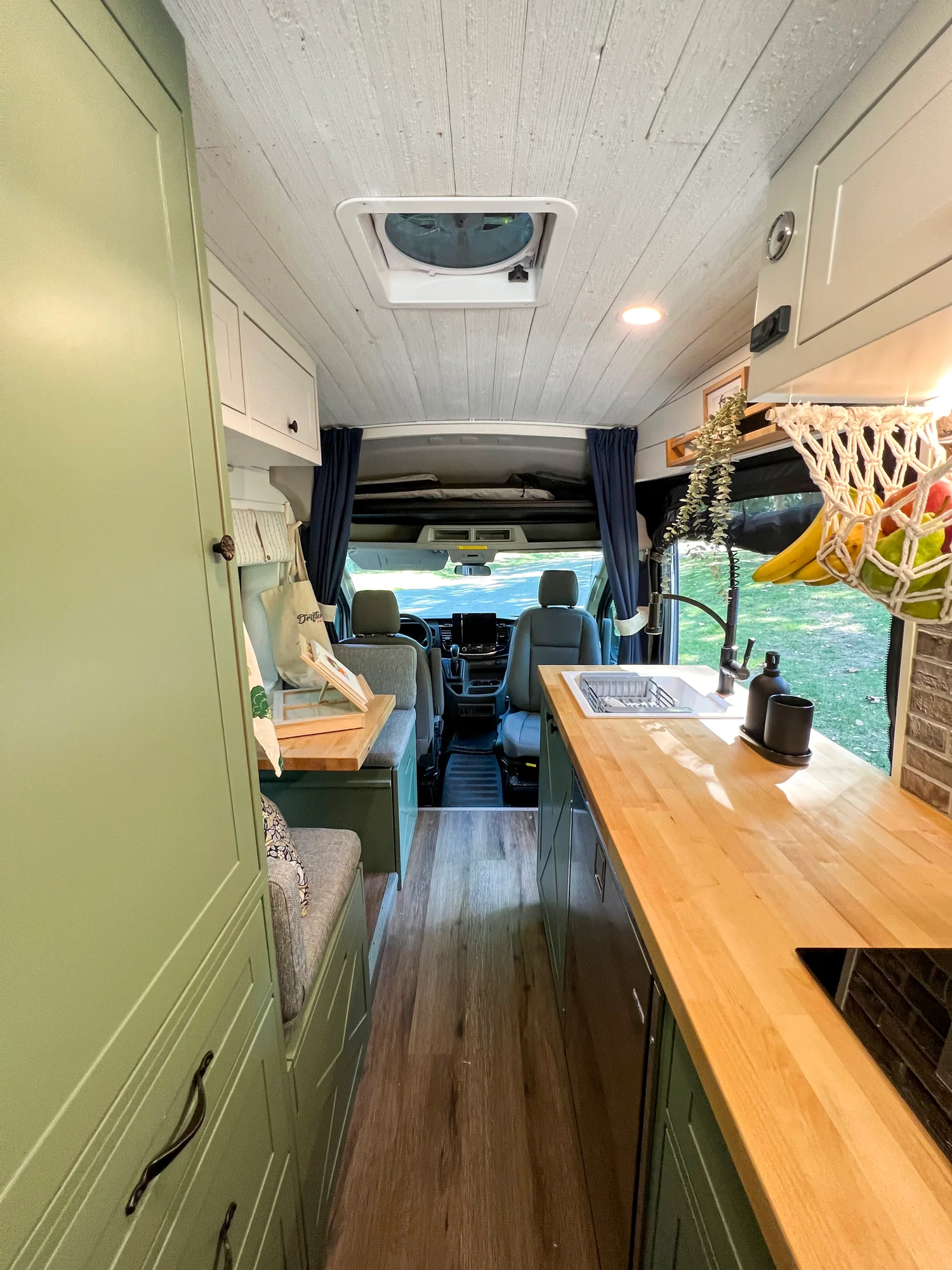The Drifter 101 custom Ford Transit campervan built for Steph and Jen by Drifter Vans, Wanderer layout with a brick backsplash, sage green cabinetry, and farmhouse lighting
