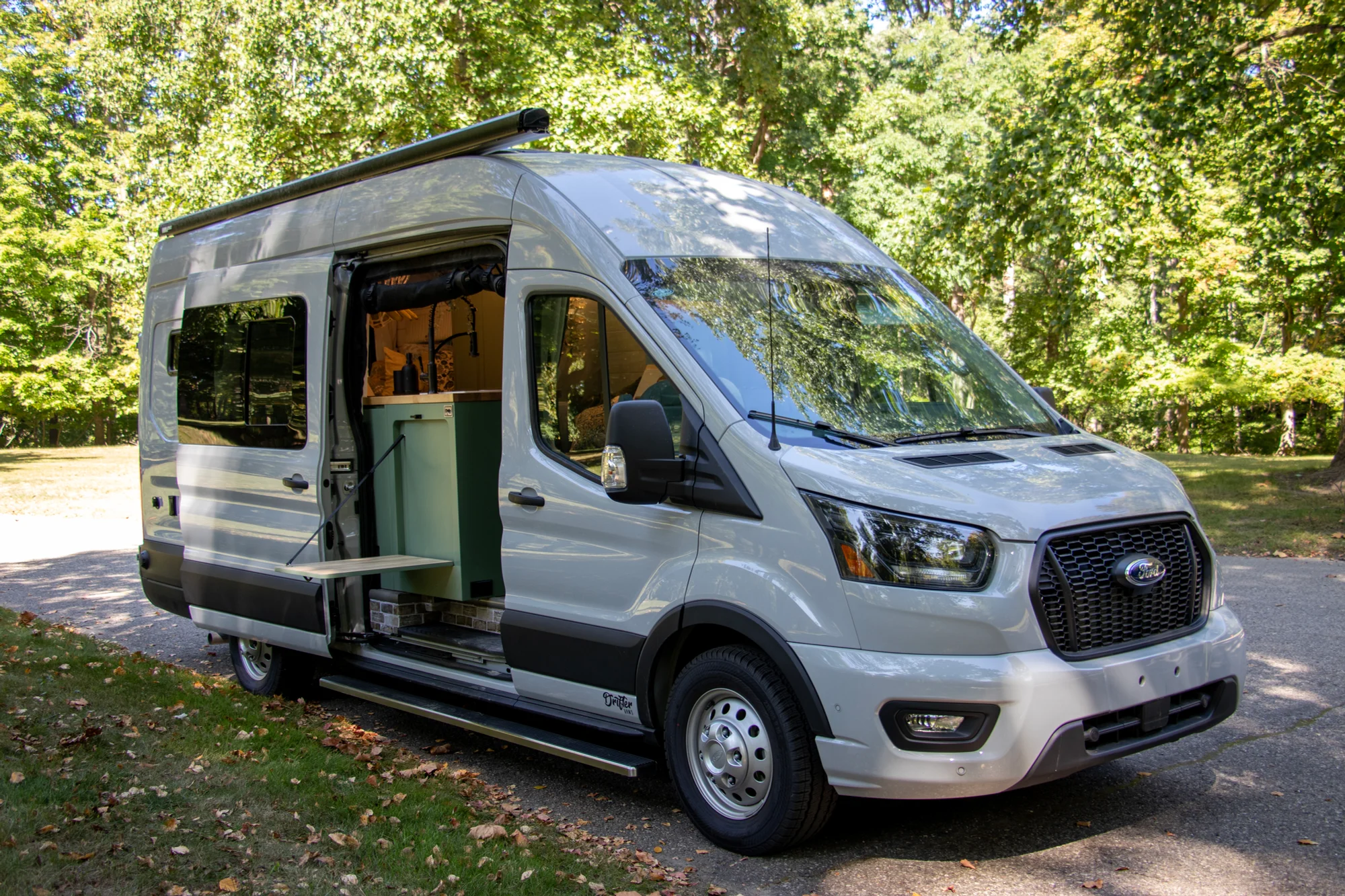 The Drifter 101 custom Ford Transit campervan built for Steph and Jen by Drifter Vans, Wanderer layout with a brick backsplash, sage green cabinetry, and farmhouse lighting