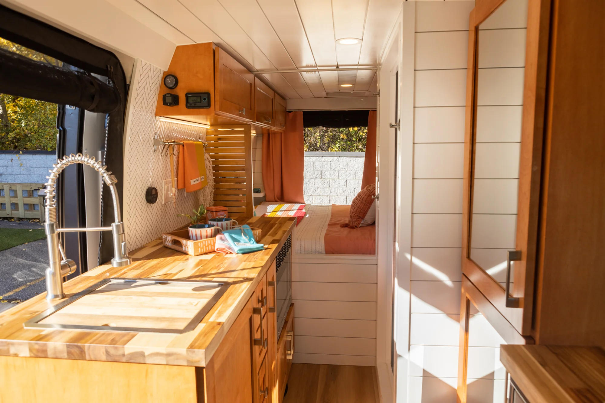 The Drifter 101 custom Ford Transit campervan built for Griff by Drifter Vans, with a bold orange and white interior, herringbone backsplash, and gray tile shower