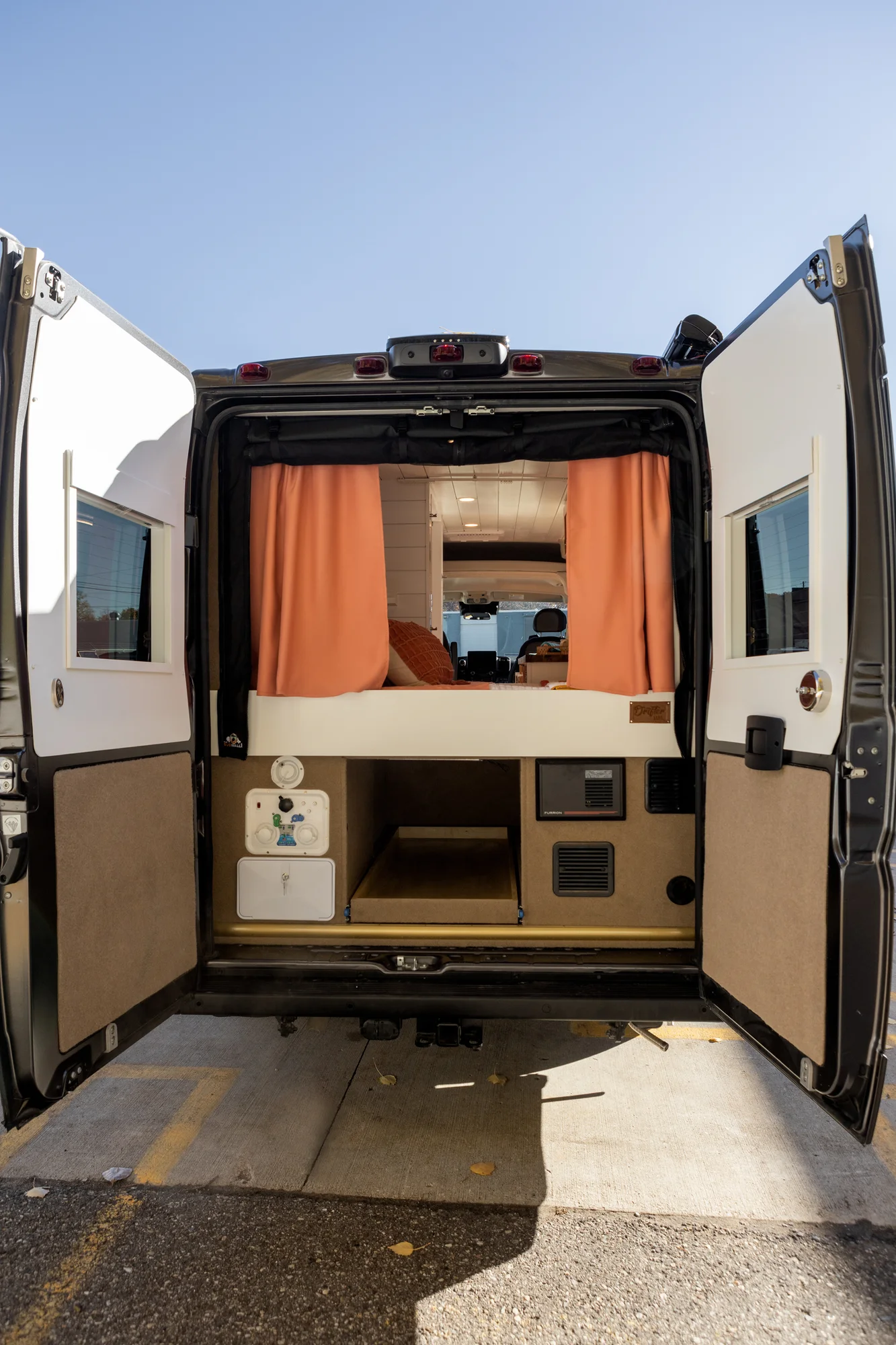 The Drifter 101 custom Ford Transit campervan built for Griff by Drifter Vans, with a bold orange and white interior, herringbone backsplash, and gray tile shower