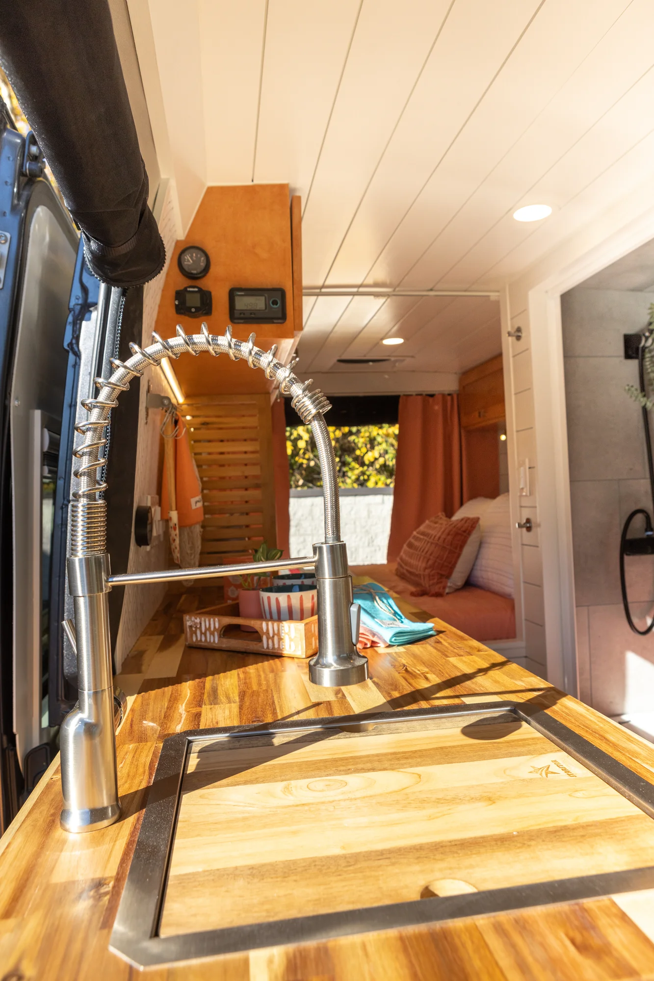 The Drifter 101 custom Ford Transit campervan built for Griff by Drifter Vans, with a bold orange and white interior, herringbone backsplash, and gray tile shower