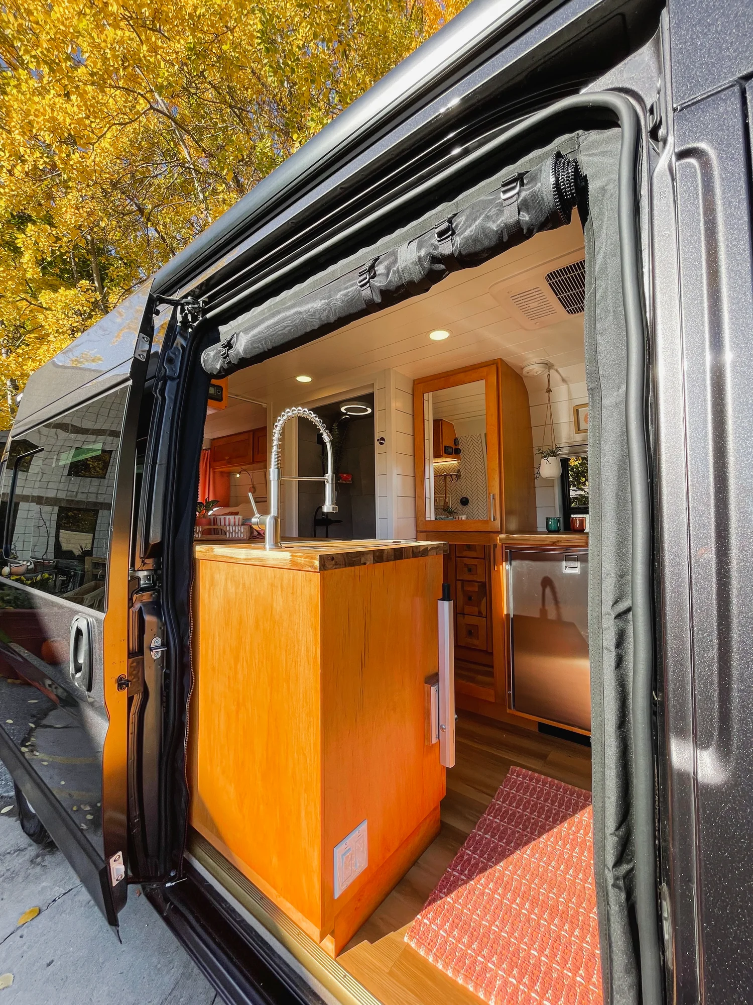 The Drifter 101 custom Ford Transit campervan built for Griff by Drifter Vans, with a bold orange and white interior, herringbone backsplash, and gray tile shower