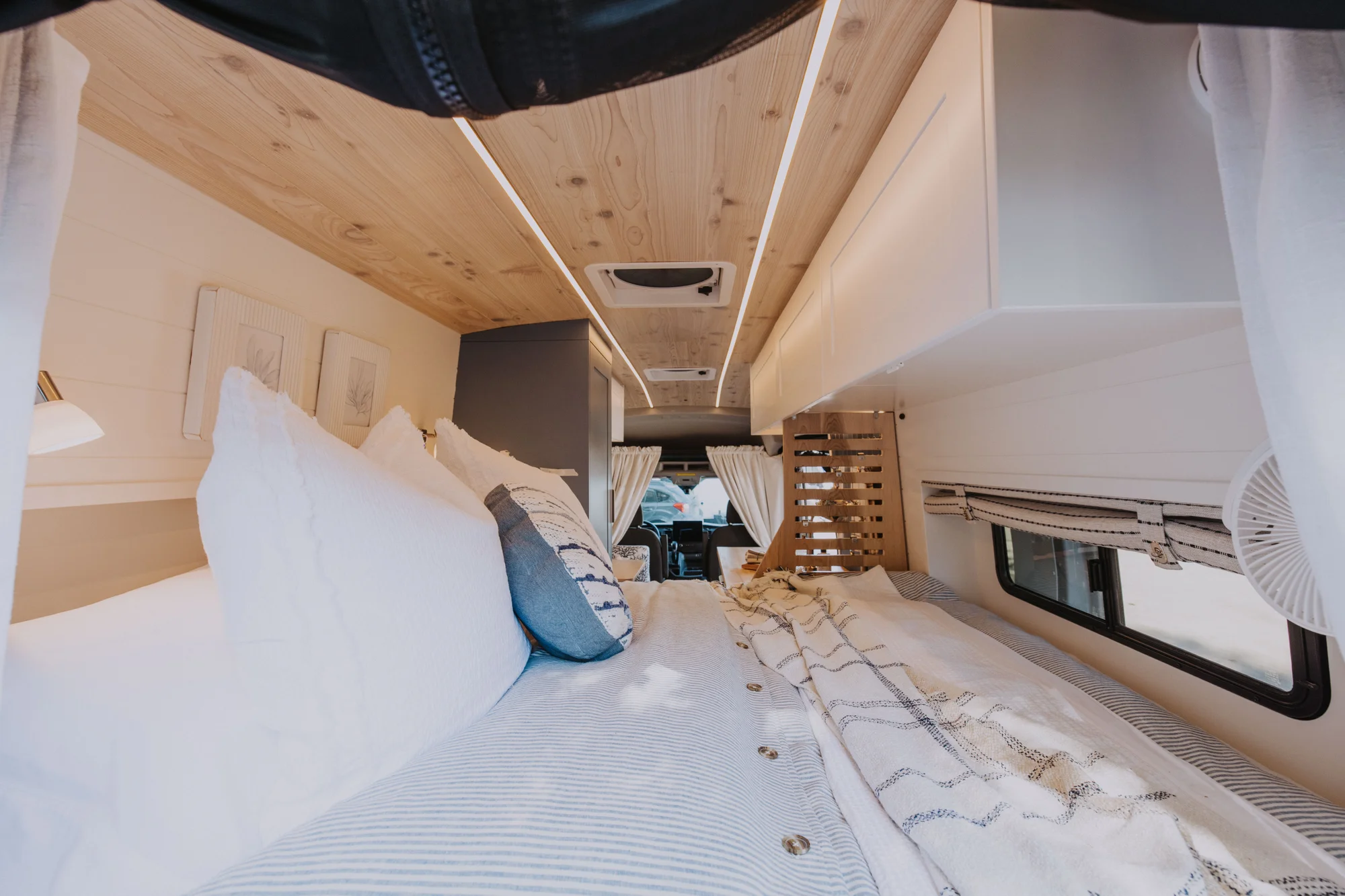 The Drifter 101 custom Ford Transit campervan built for Ayala by Drifter Vans, Drifter layout with warm wood cabinetry, a blue backsplash, flip-down shower, and an Avalanche Grey exterior