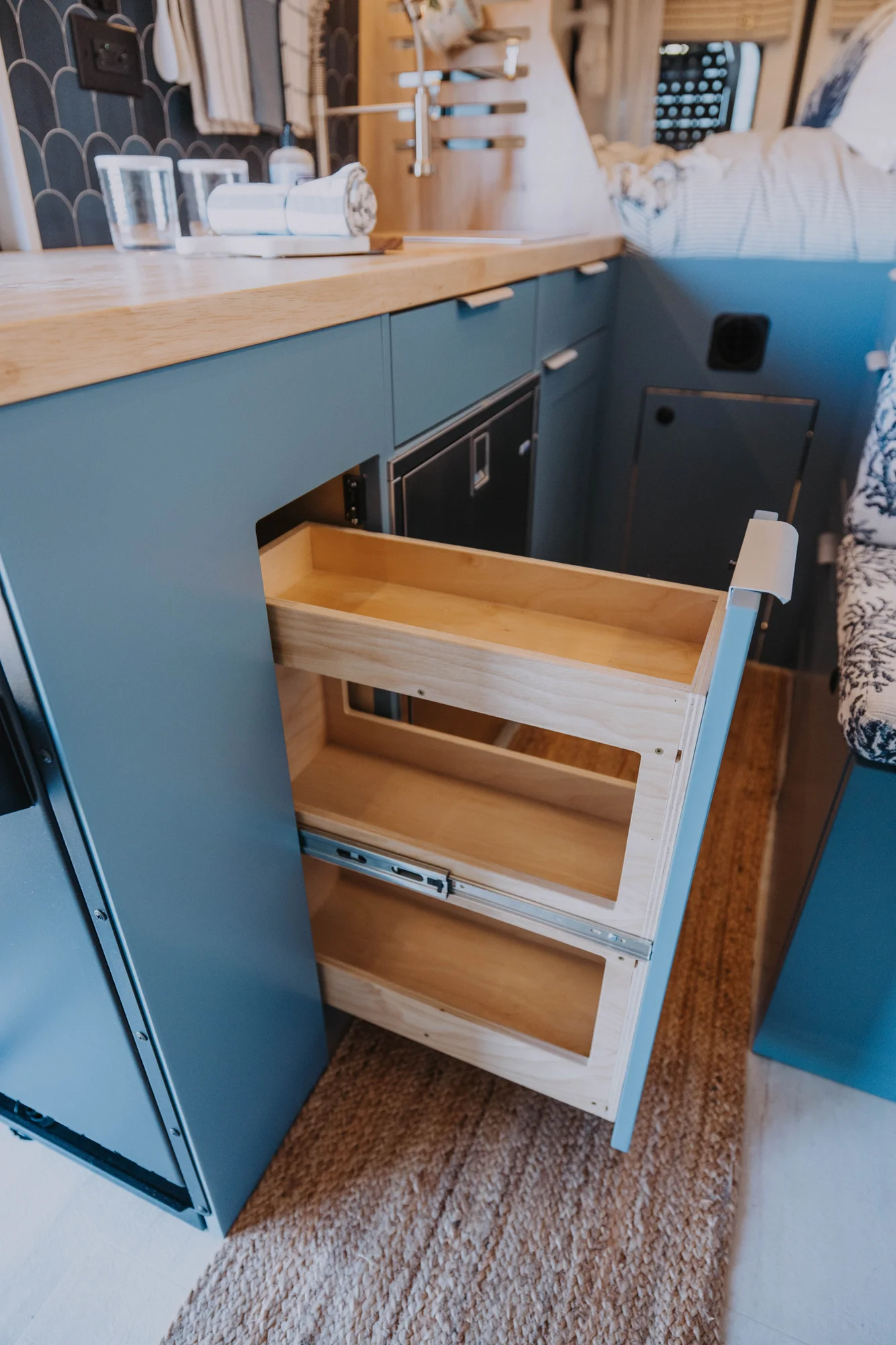 The Drifter 101 custom Ford Transit campervan built for Ayala by Drifter Vans, Drifter layout with warm wood cabinetry, a blue backsplash, flip-down shower, and an Avalanche Grey exterior