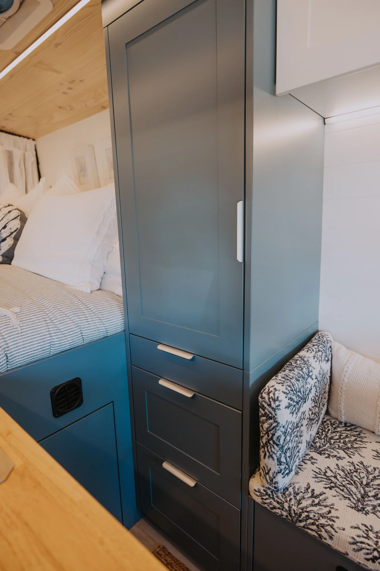 The Drifter 101 custom Ford Transit campervan built for Ayala by Drifter Vans, Drifter layout with warm wood cabinetry, a blue backsplash, flip-down shower, and an Avalanche Grey exterior
