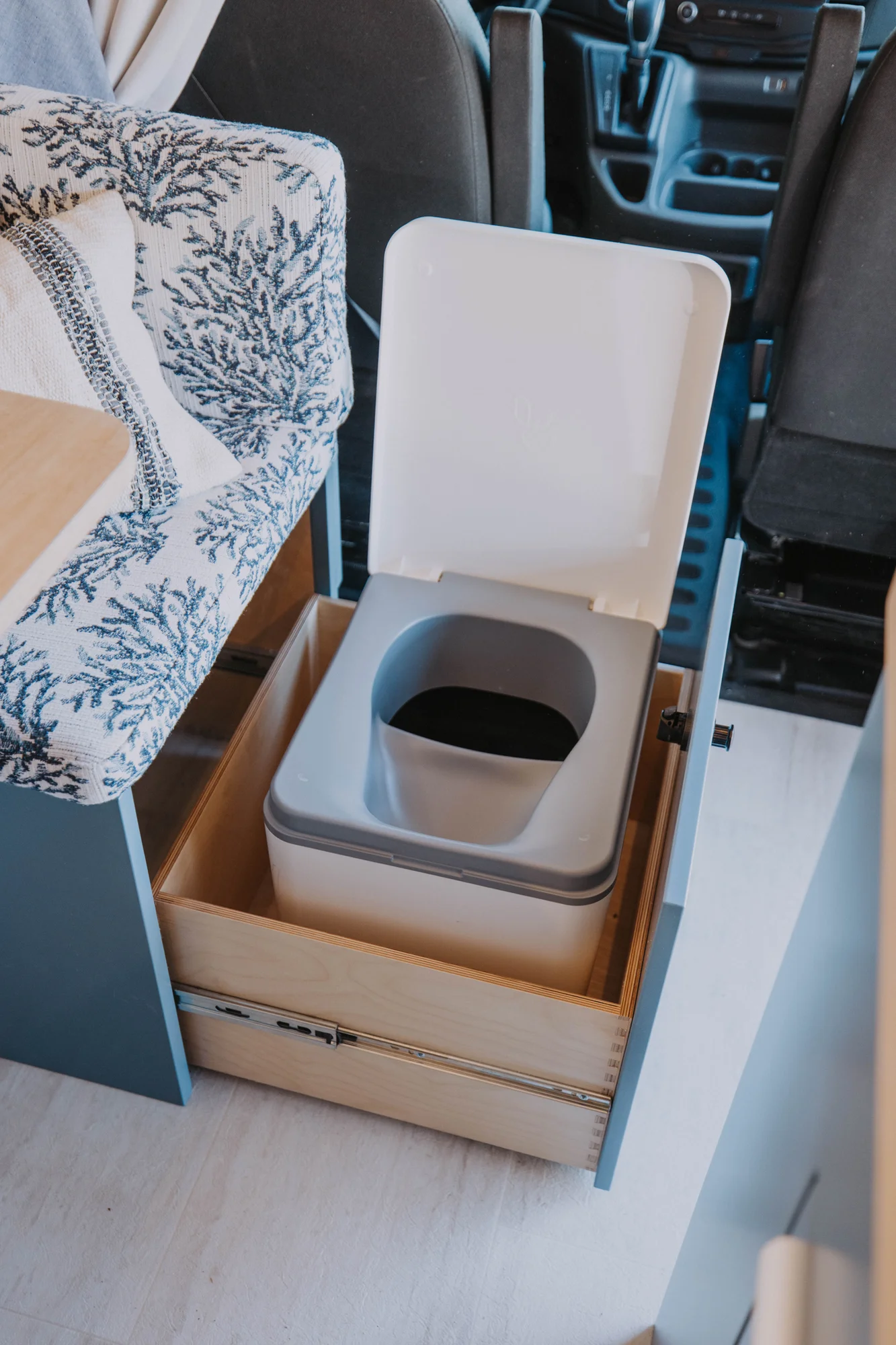 The Drifter 101 custom Ford Transit campervan built for Ayala by Drifter Vans, Drifter layout with warm wood cabinetry, a blue backsplash, flip-down shower, and an Avalanche Grey exterior