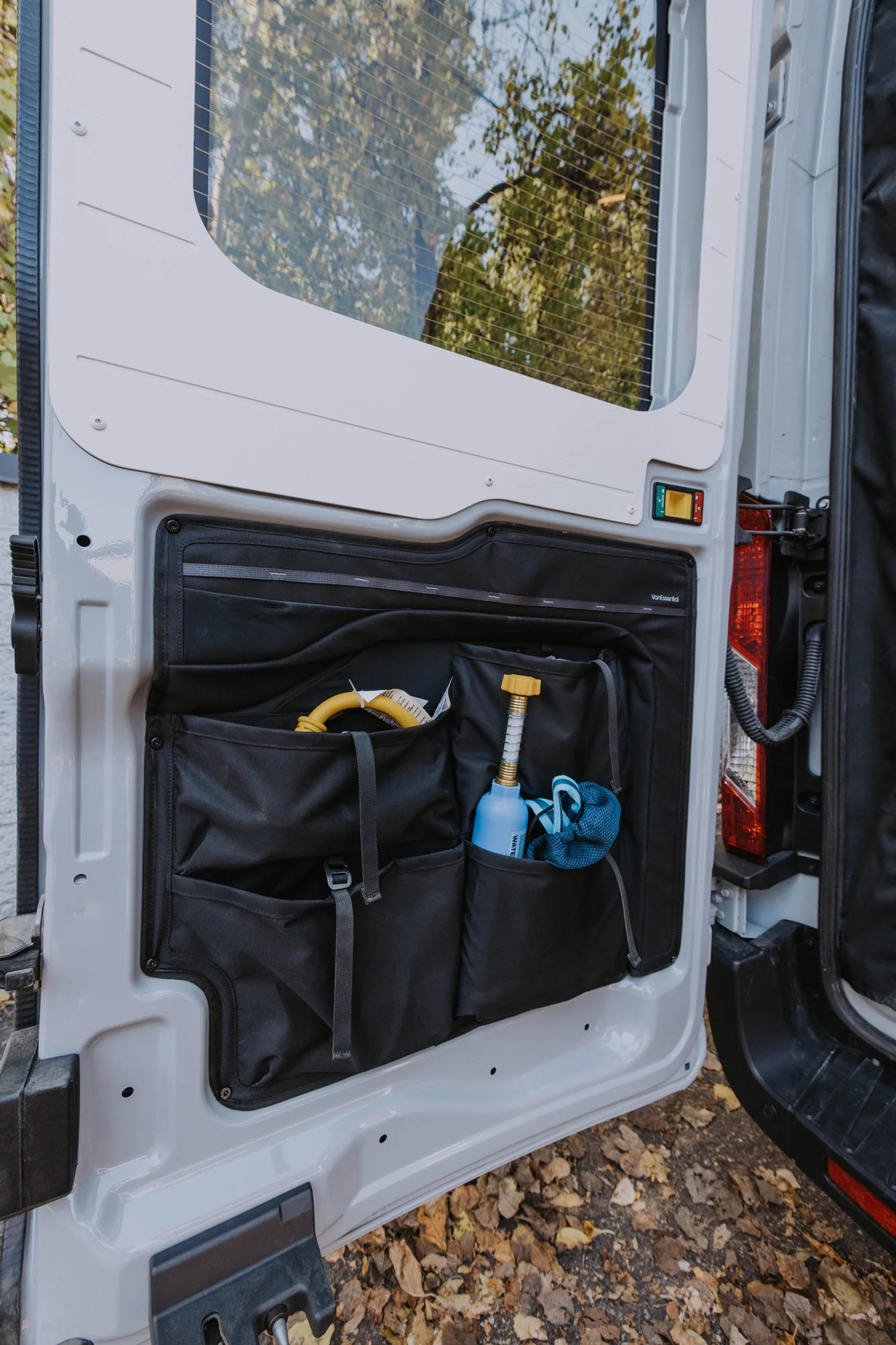 The Drifter 101 custom Ford Transit campervan built for Ayala by Drifter Vans, Drifter layout with warm wood cabinetry, a blue backsplash, flip-down shower, and an Avalanche Grey exterior