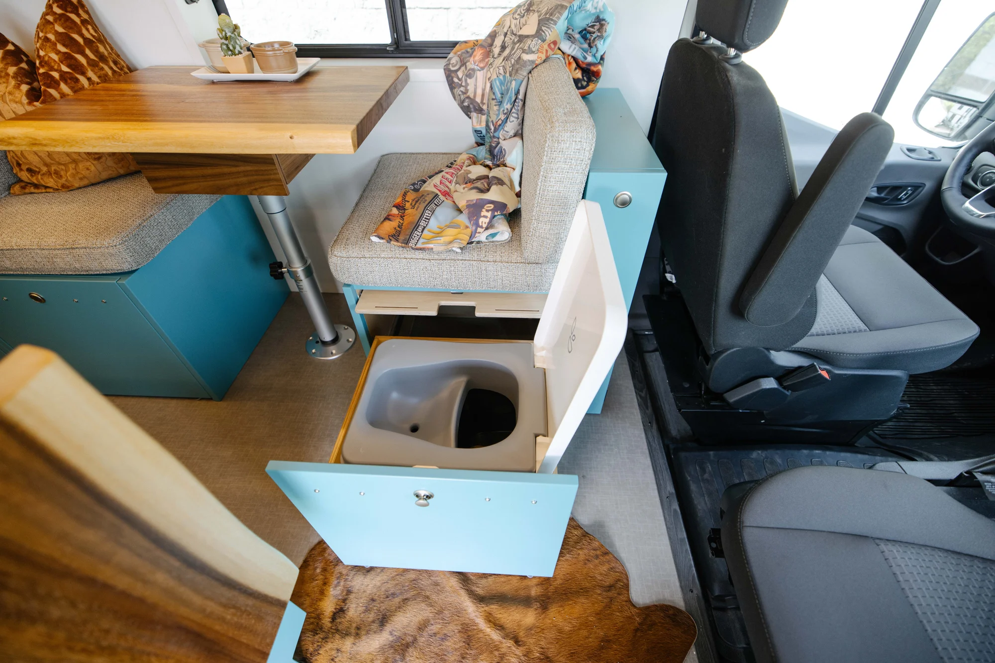 The Drifter 101 custom Ford Transit campervan built for Zach and Stephanie by Drifter Vans, with turquoise cabinetry, a custom wine rack, and Texas-inspired mid-century details