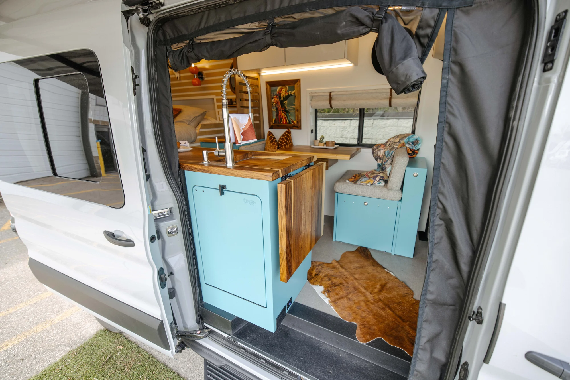 The Drifter 101 custom Ford Transit campervan built for Zach and Stephanie by Drifter Vans, with turquoise cabinetry, a custom wine rack, and Texas-inspired mid-century details