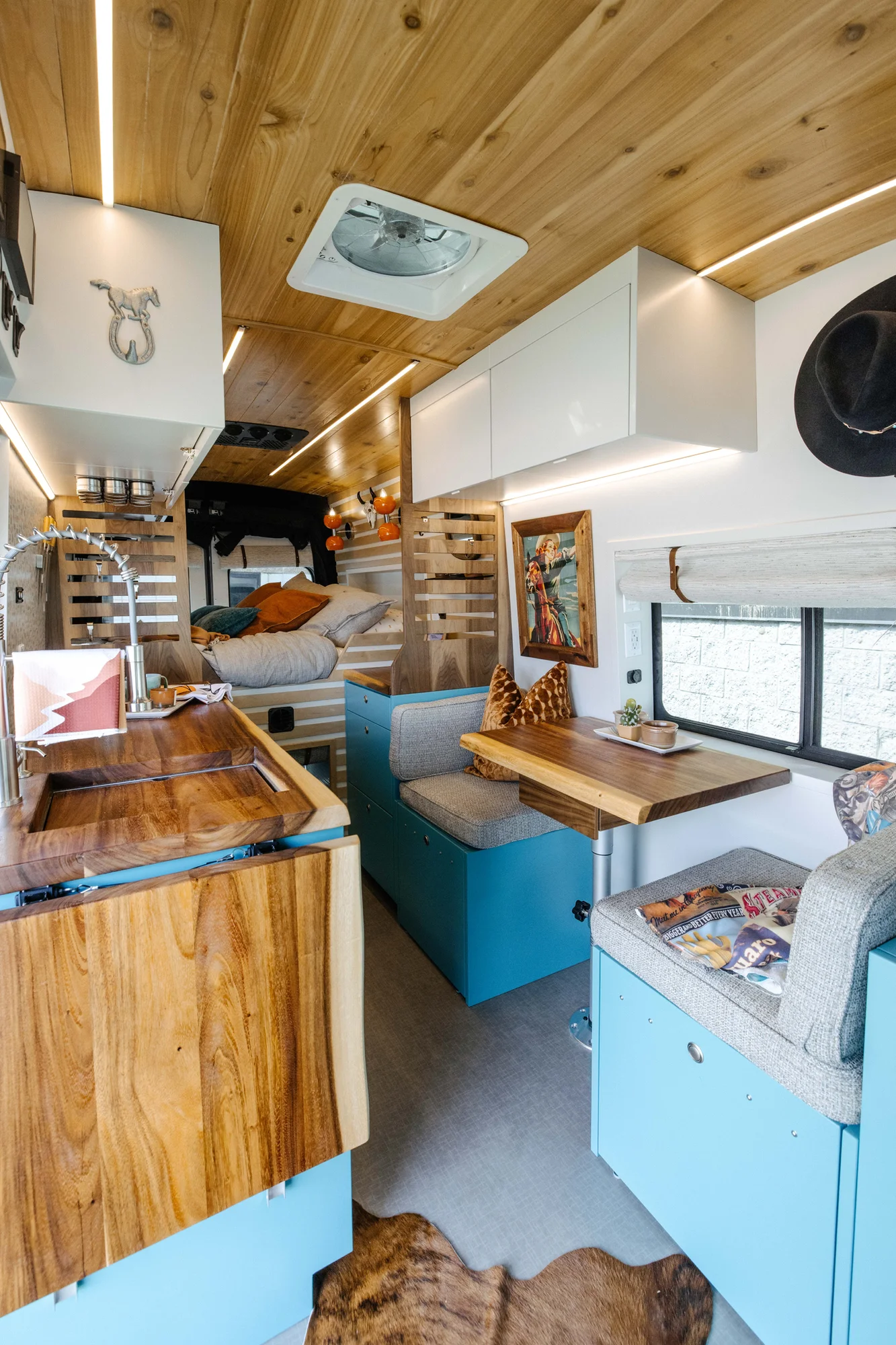 The Drifter 101 custom Ford Transit campervan built for Zach and Stephanie by Drifter Vans, with turquoise cabinetry, a custom wine rack, and Texas-inspired mid-century details
