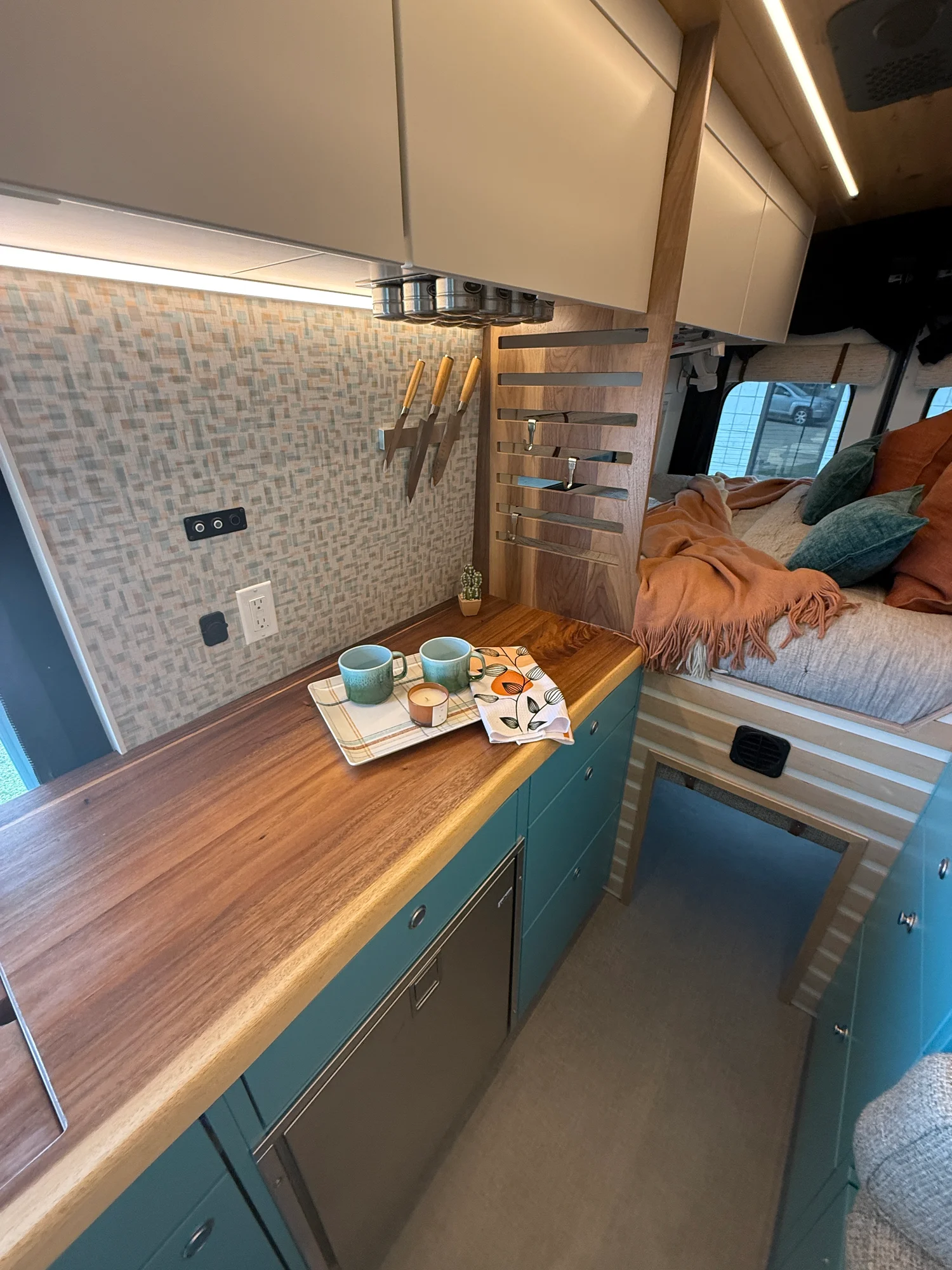 The Drifter 101 custom Ford Transit campervan built for Zach and Stephanie by Drifter Vans, with turquoise cabinetry, a custom wine rack, and Texas-inspired mid-century details