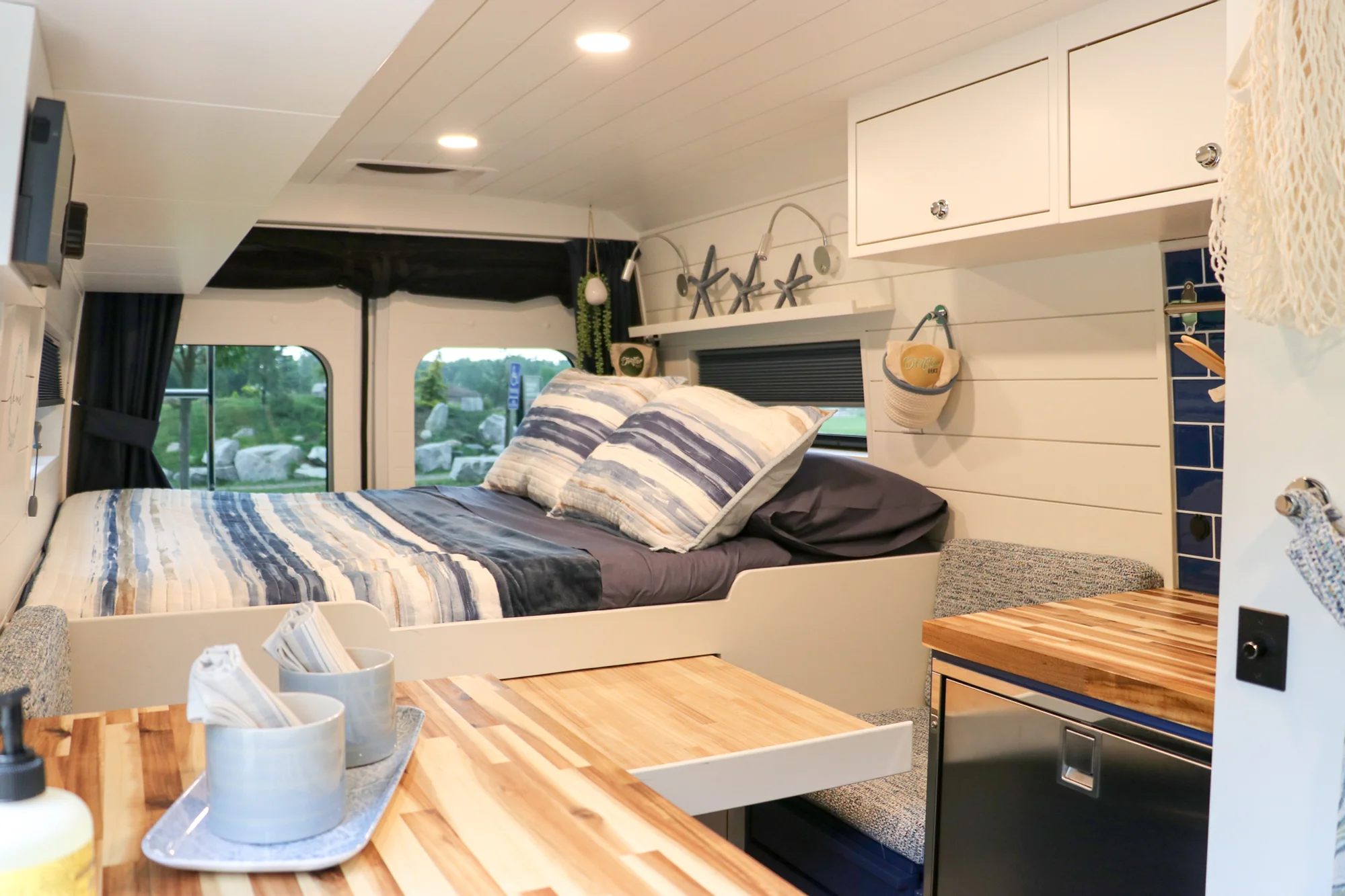 The Drifter 101 custom Ram ProMaster campervan built for Karen by Drifter Vans, Nomadik layout with coastal blue cabinetry, subway tile backsplash, and a white marble wet bath