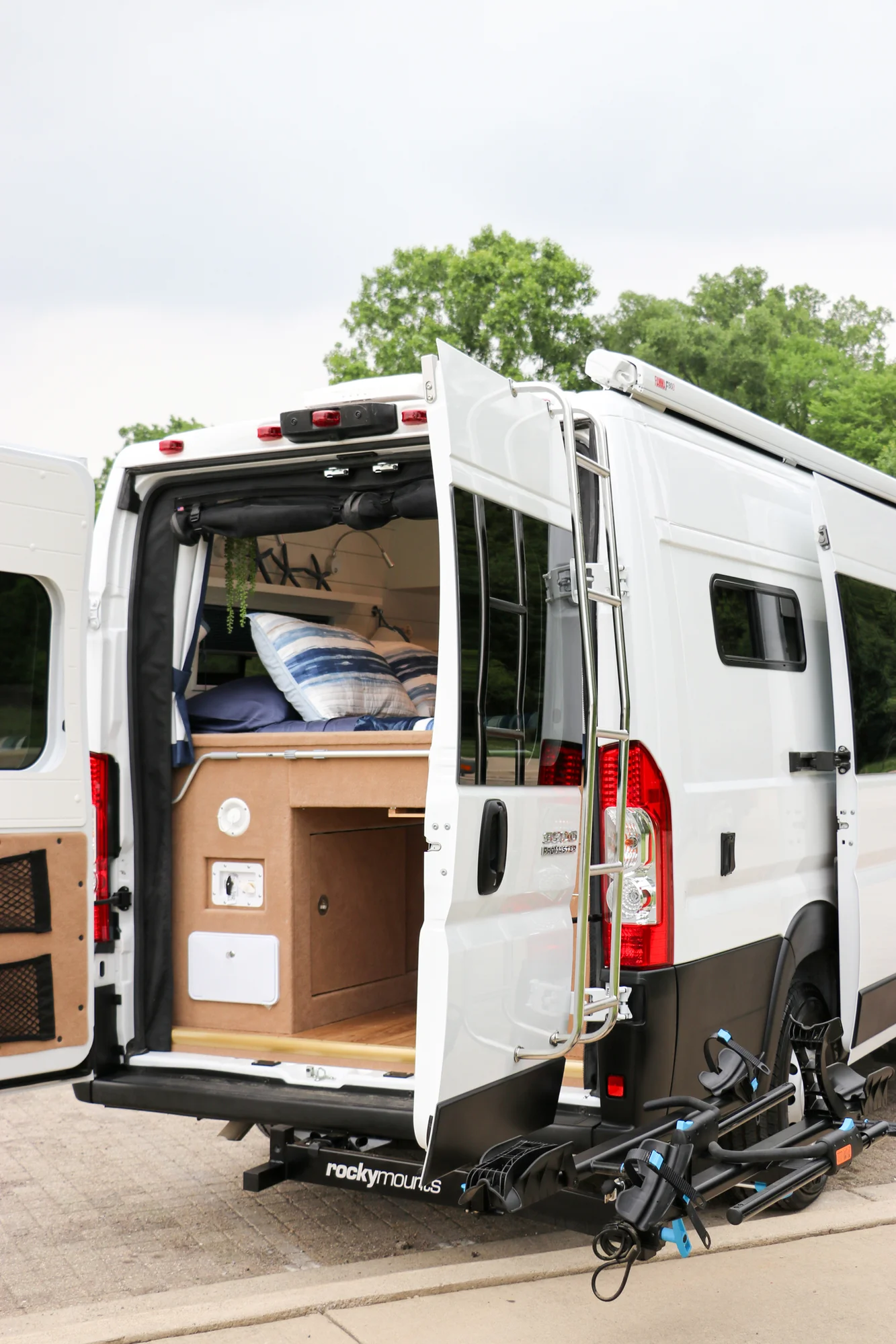 The Drifter 101 custom Ram ProMaster campervan built for Karen by Drifter Vans, Nomadik layout with coastal blue cabinetry, subway tile backsplash, and a white marble wet bath