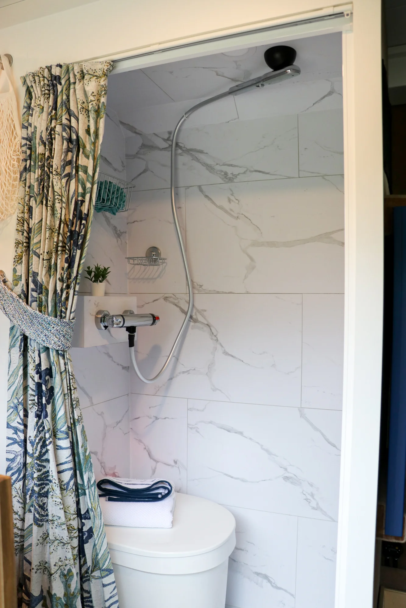 The Drifter 101 custom Ram ProMaster campervan built for Karen by Drifter Vans, Nomadik layout with coastal blue cabinetry, subway tile backsplash, and a white marble wet bath