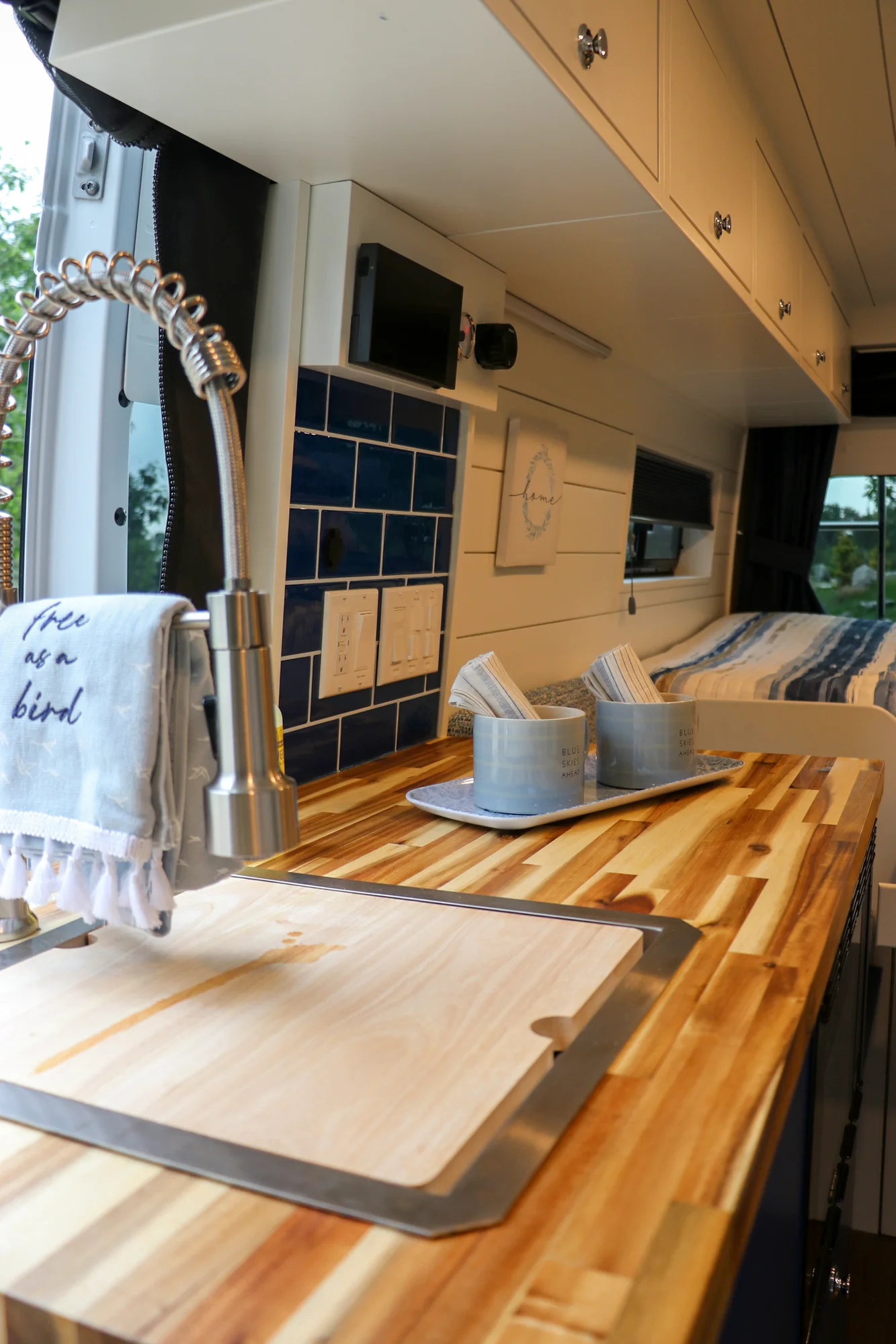 The Drifter 101 custom Ram ProMaster campervan built for Karen by Drifter Vans, Nomadik layout with coastal blue cabinetry, subway tile backsplash, and a white marble wet bath