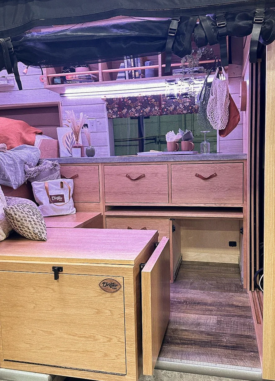 The Drifter 101 custom Ford Transit campervan built for Gardner by Drifter Vans, with warm wood paneling, earthy tones, soft seating, and modular storage
