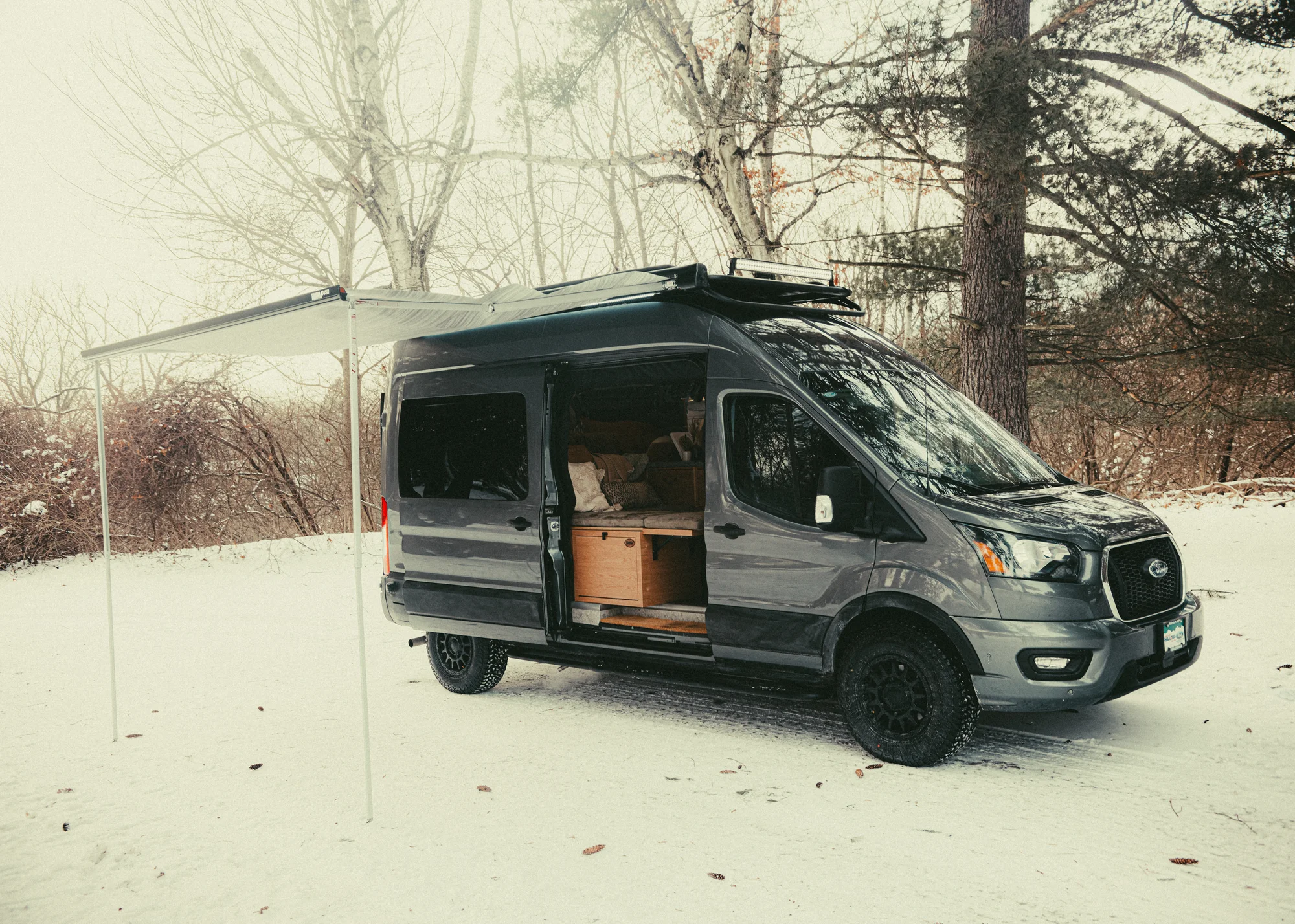The Drifter 101 custom Ford Transit campervan built for Gardner by Drifter Vans, with warm wood paneling, earthy tones, soft seating, and modular storage