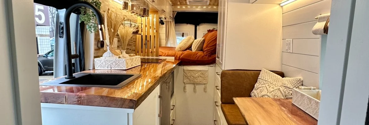 The Drifter 101 custom Ford Transit campervan built for Meredith by Drifter Vans, Wanderer layout with an earthy boho interior, rust linen bedding, and a natural wood countertop