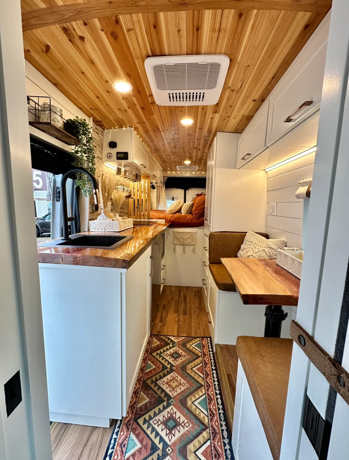 The Drifter 101 custom Ford Transit campervan built for Meredith by Drifter Vans, Wanderer layout with an earthy boho interior, rust linen bedding, and a natural wood countertop