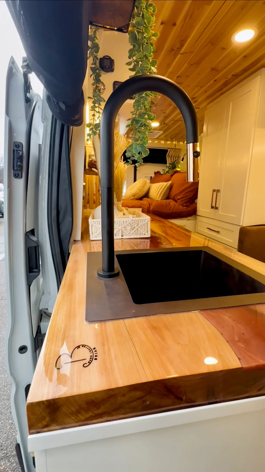 The Drifter 101 custom Ford Transit campervan built for Meredith by Drifter Vans, Wanderer layout with an earthy boho interior, rust linen bedding, and a natural wood countertop