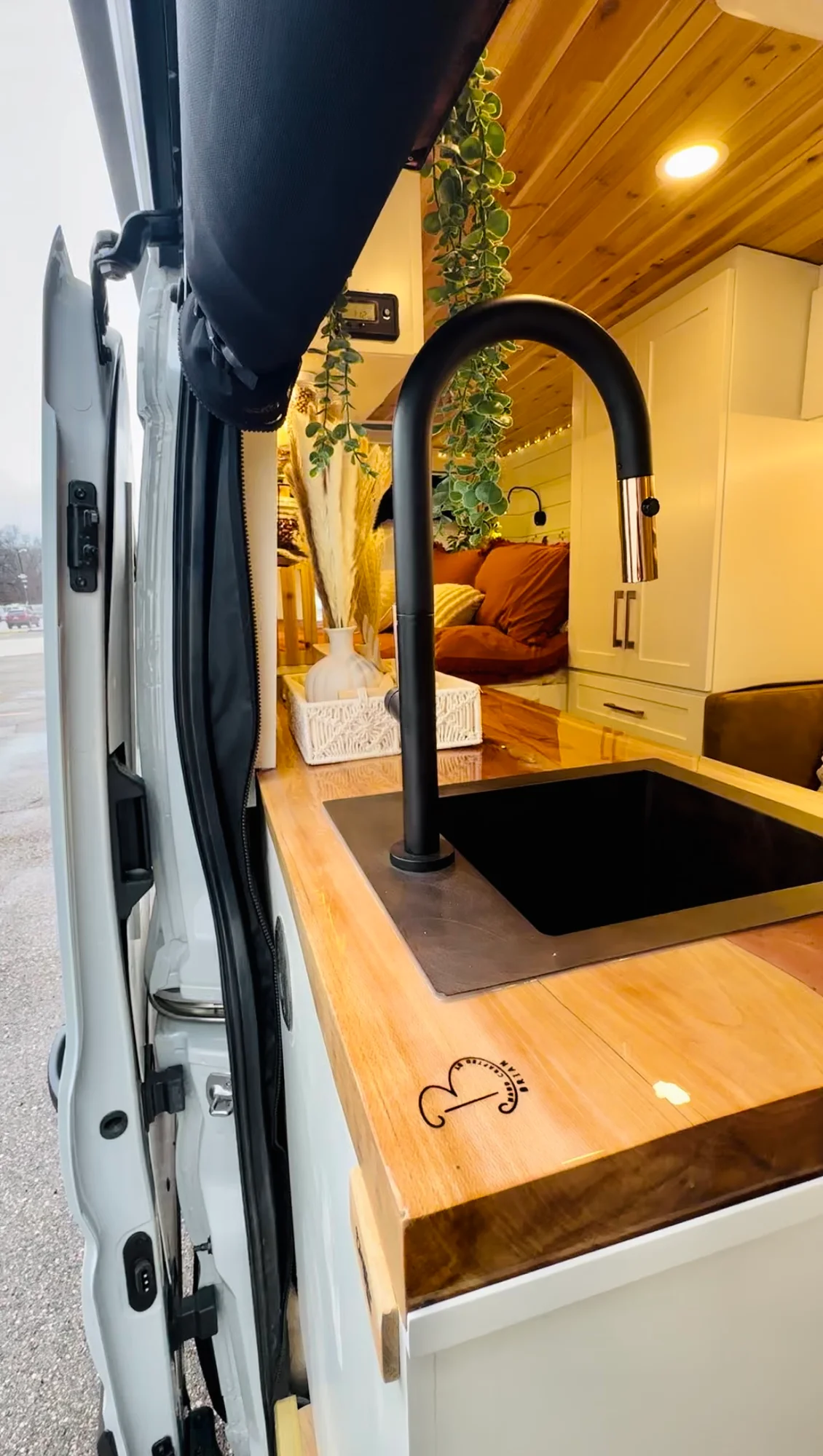 The Drifter 101 custom Ford Transit campervan built for Meredith by Drifter Vans, Wanderer layout with an earthy boho interior, rust linen bedding, and a natural wood countertop