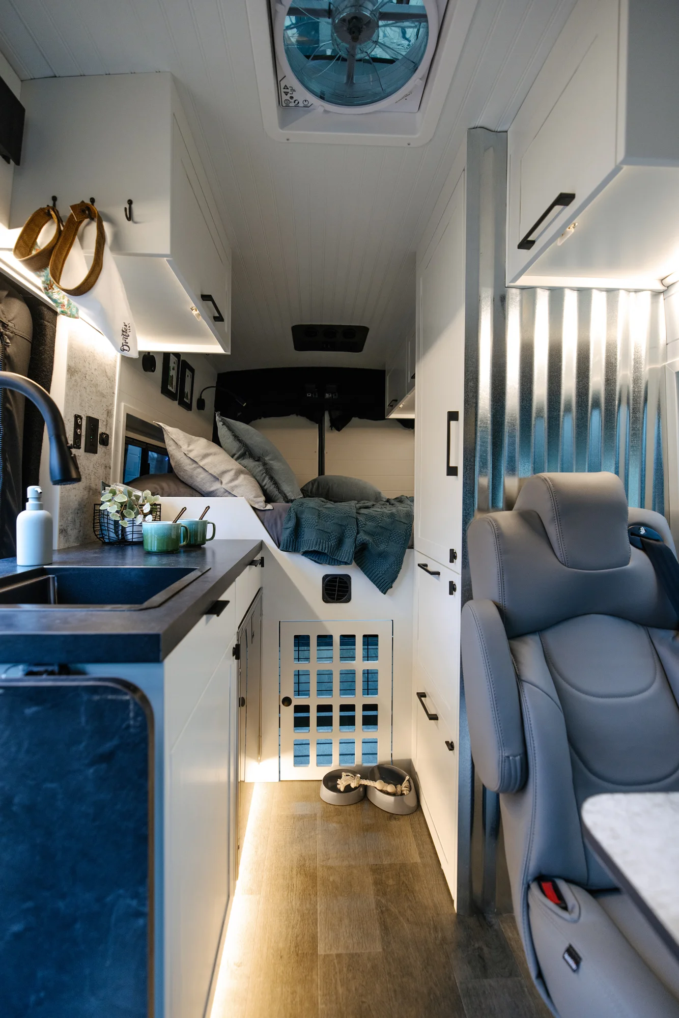 The Drifter 101 custom Ford Transit campervan built for Lisa by Drifter Vans, Wanderer layout with a beachy coastal interior, light blue and white finishes, dog-friendly built-ins, and a swivel chair
