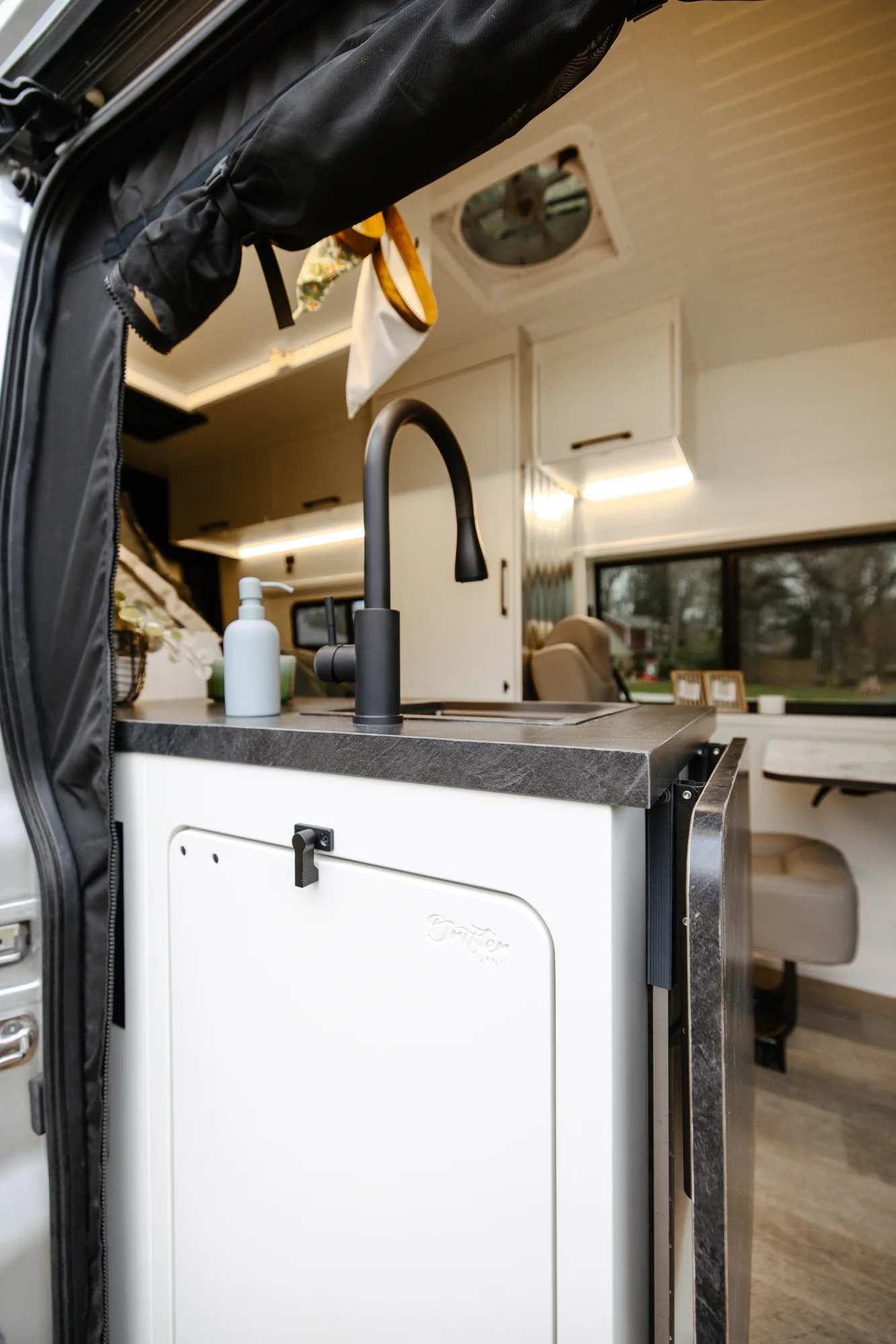 The Drifter 101 custom Ford Transit campervan built for Lisa by Drifter Vans, Wanderer layout with a beachy coastal interior, light blue and white finishes, dog-friendly built-ins, and a swivel chair