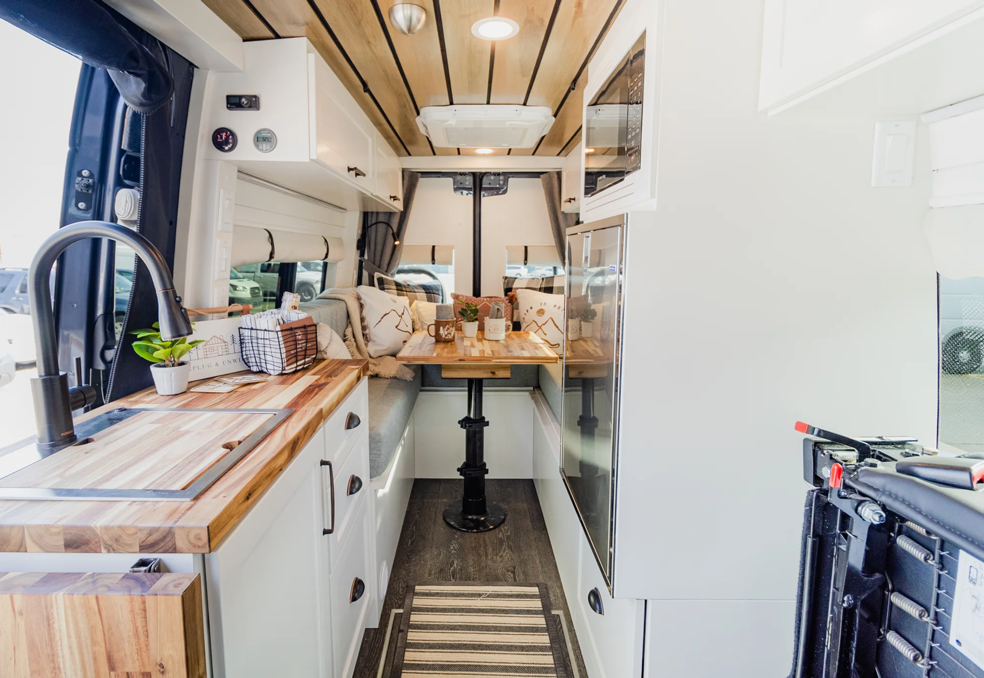 The Drifter 101 custom Mercedes-Benz Sprinter campervan built for Dave by Drifter Vans, with a wood plank ceiling, butcher block countertop, black faucet, and stainless appliances
