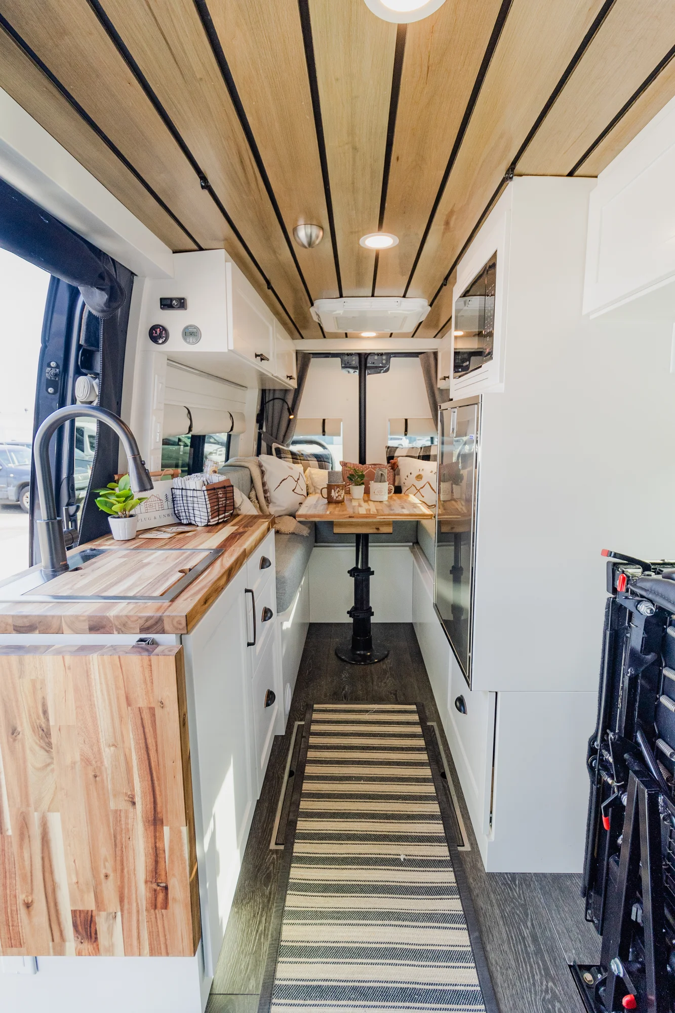 The Drifter 101 custom Mercedes-Benz Sprinter campervan built for Dave by Drifter Vans, with a wood plank ceiling, butcher block countertop, black faucet, and stainless appliances