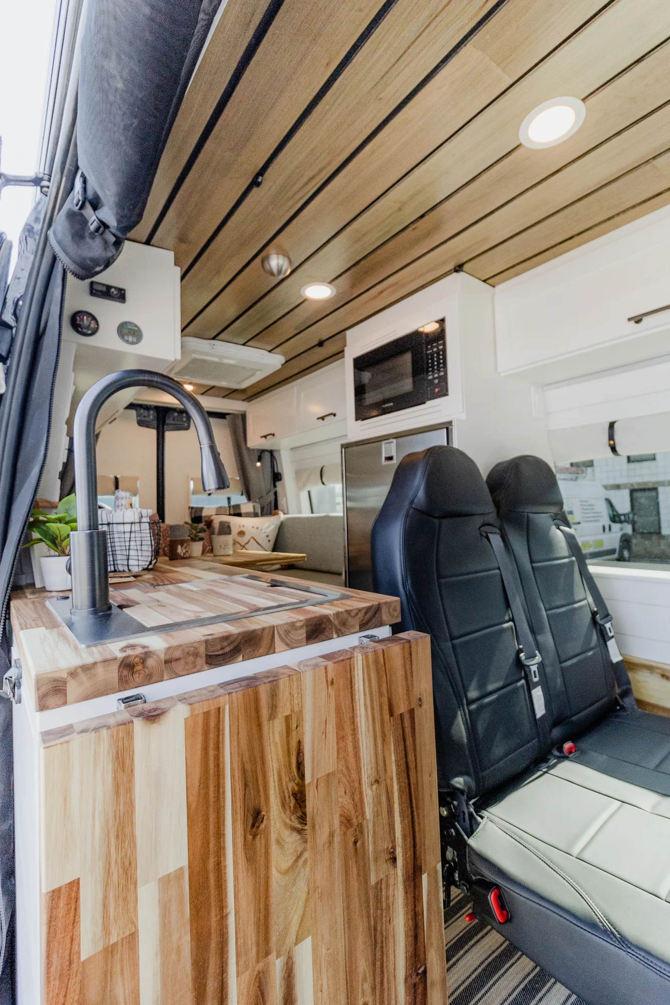 The Drifter 101 custom Mercedes-Benz Sprinter campervan built for Dave by Drifter Vans, with a wood plank ceiling, butcher block countertop, black faucet, and stainless appliances