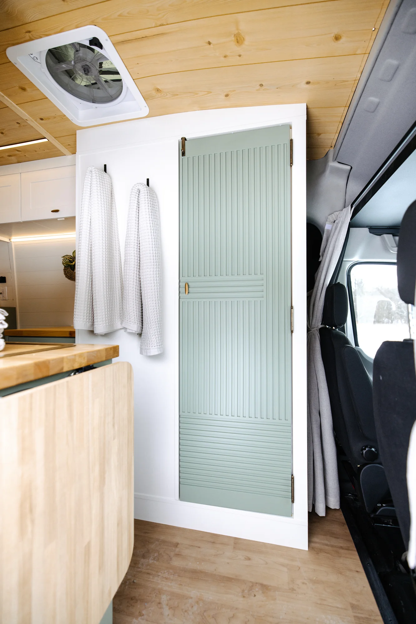 The Drifter 101 custom Ford Transit campervan built for Adrianne by Drifter Vans, Nomadik layout with knotty pine accents, soft green cabinetry, and a gold rain shower