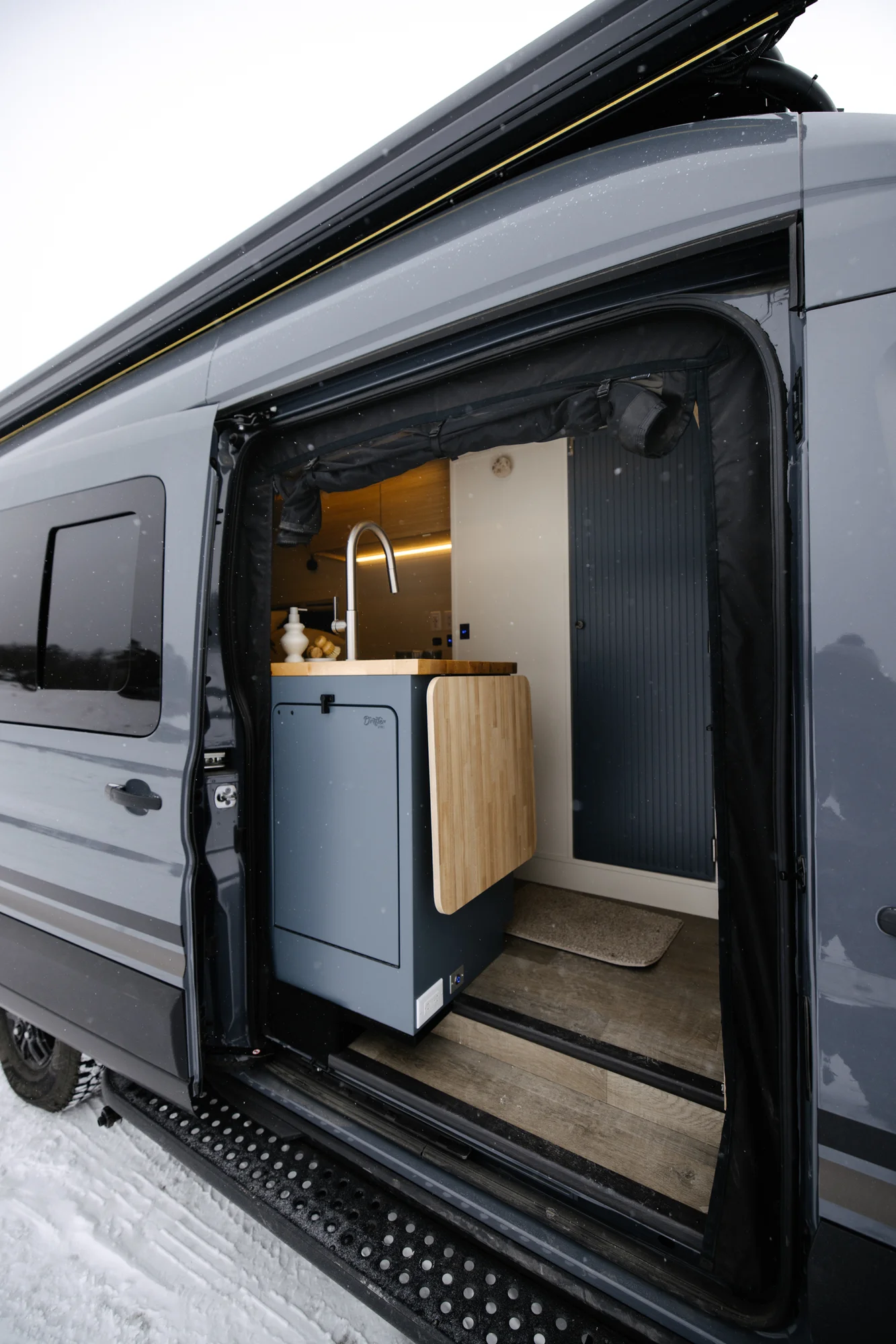 The Drifter 101 custom Ford Transit campervan built for Dan and Karen by Drifter Vans, Nomadik layout with an Indian autumn stone wet bath, trifold door, Aluminus bumper, and FVCO roof rack