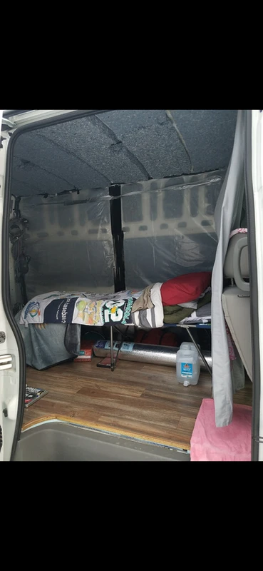Early van life for a travel nurse – minimalist interior with a cot and basic storage in Tess’s cheap first van build