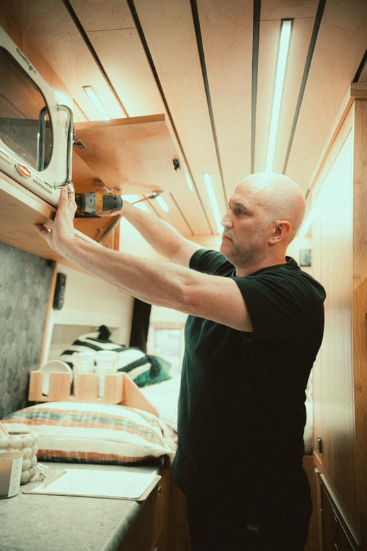 Paul Domish inside a drifter van putting together the cabinet