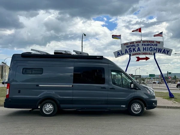 Mallory and Matt's Drifter Van parked in front of the world-famous Alaska Highway sign, marking a milestone in their vanlife journey.
