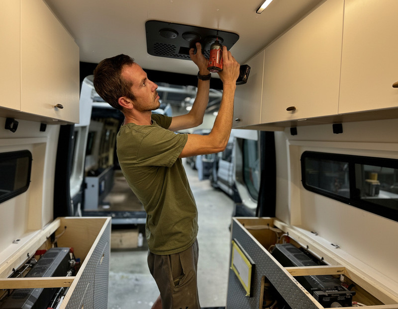 Three members of the Drifter workshop team collaborating on a custom campervan build, focused on craftsmanship and precision.