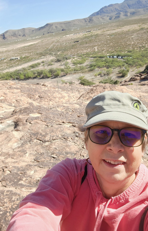 Susan Lebold takes a selfie with a sweeping scenic view behind her—open road, rolling hills, and a sense of freedom captured in the moment.