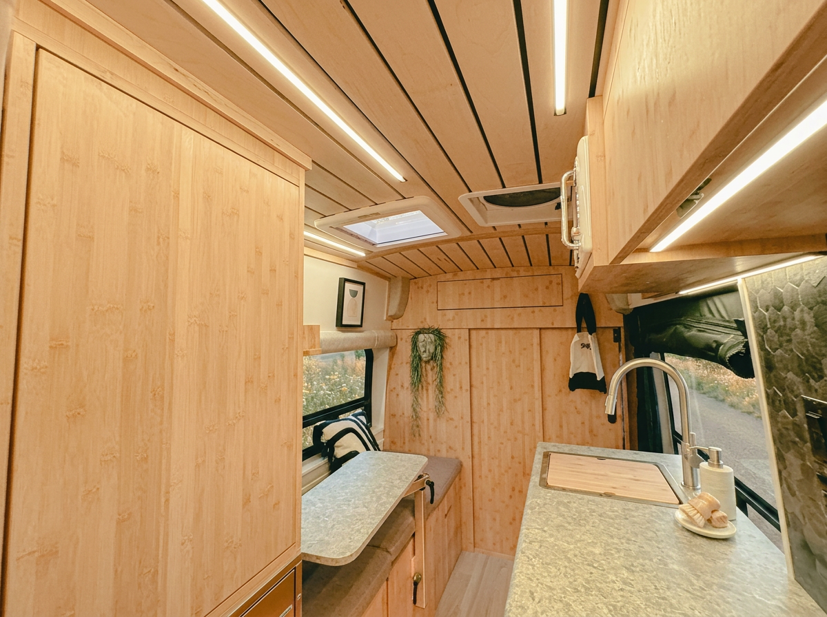The Drifter 101 custom Ford Transit campervan built for Debra by Drifter Vans, with natural bamboo cabinetry, a skylight, LED ambient lighting, and a stone-style countertop