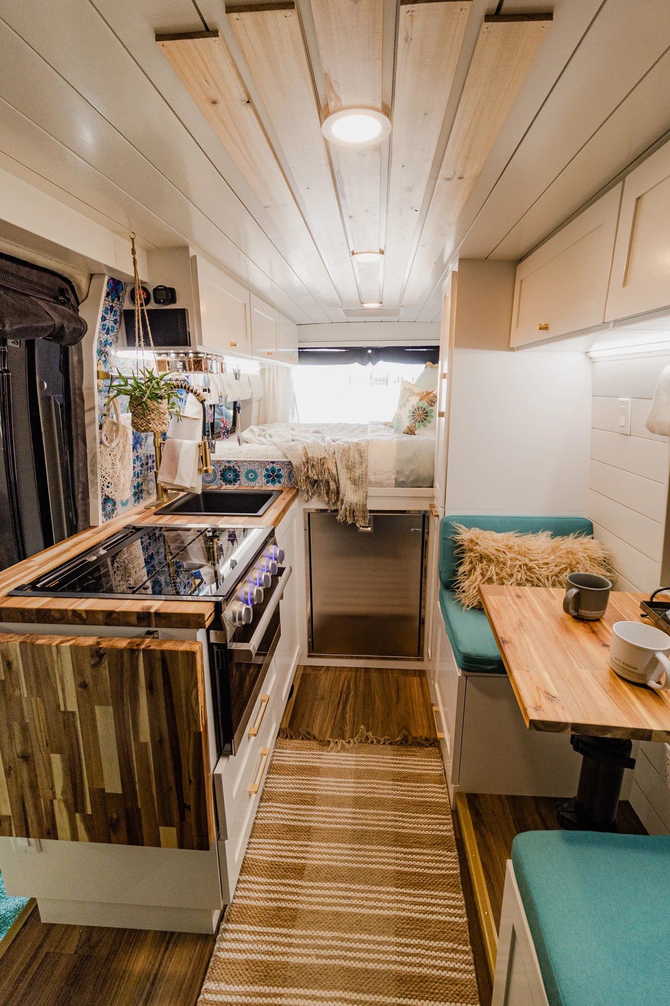 The Drifter 101 custom Ram ProMaster campervan built for Rhonda by Drifter Vans, Wanderer layout with a boho interior, Furrion oven, blue patterned tile backsplash, and brass hardware