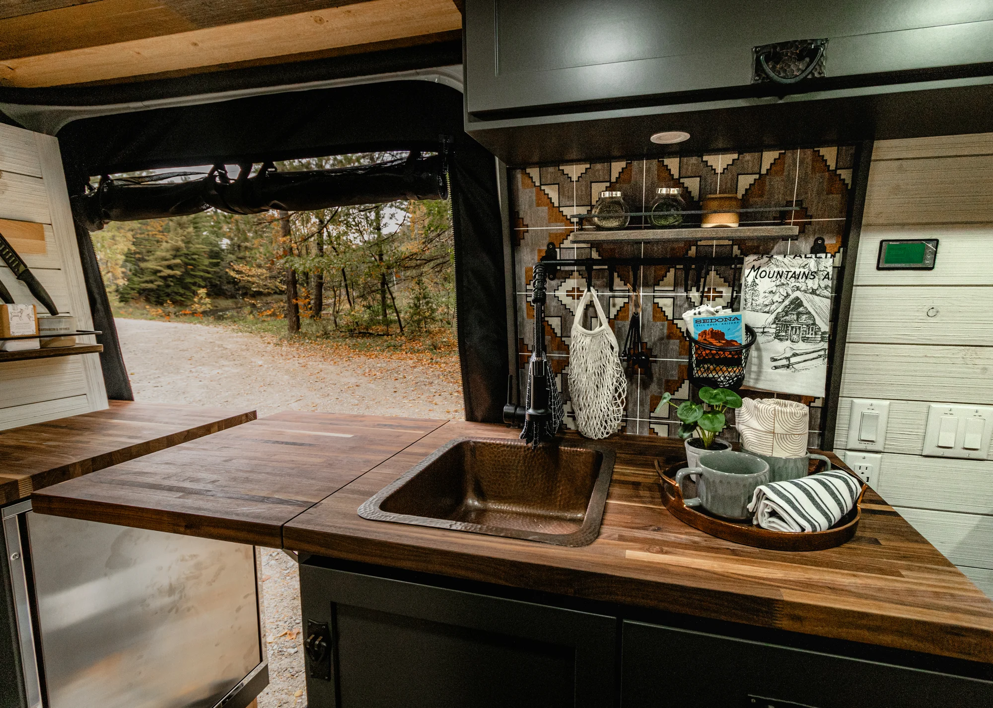 The Drifter 101 custom Mercedes-Benz Sprinter campervan built for Roger and Melisa by Drifter Vans, with a porthole wood shower door, dark wood interior, Southwest-style backsplash, and cast iron hardware