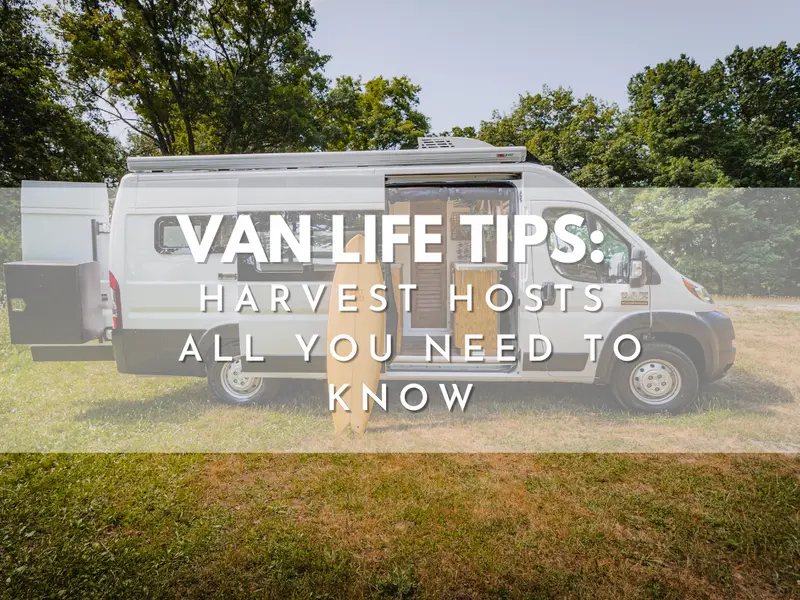 Van life tips cover: Harvest Hosts guide for campervans, white camper van parked on grass with side door open and surfboard leaning against it