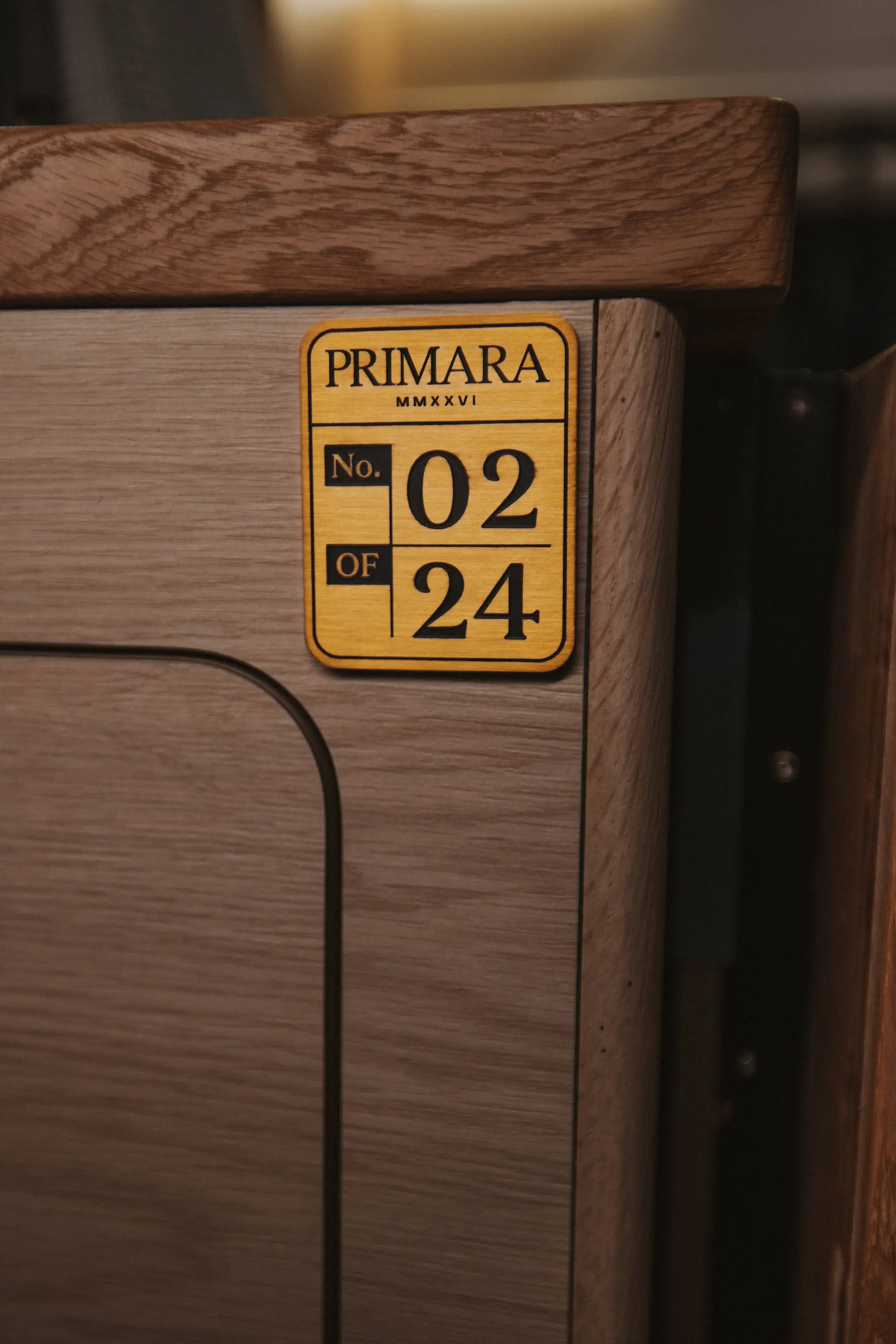 Drifter Primara Collection build 02 of 24: numbered brass edition badge mounted on white oak cabinetry, marking Primara No. 02 of 24