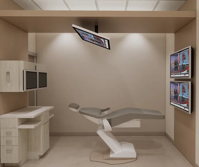 Dental examination room with a reclining chair and wall-mounted screens displaying images.