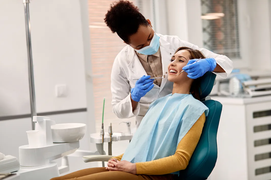 A dentist examines a woman's teeth in a dental office.